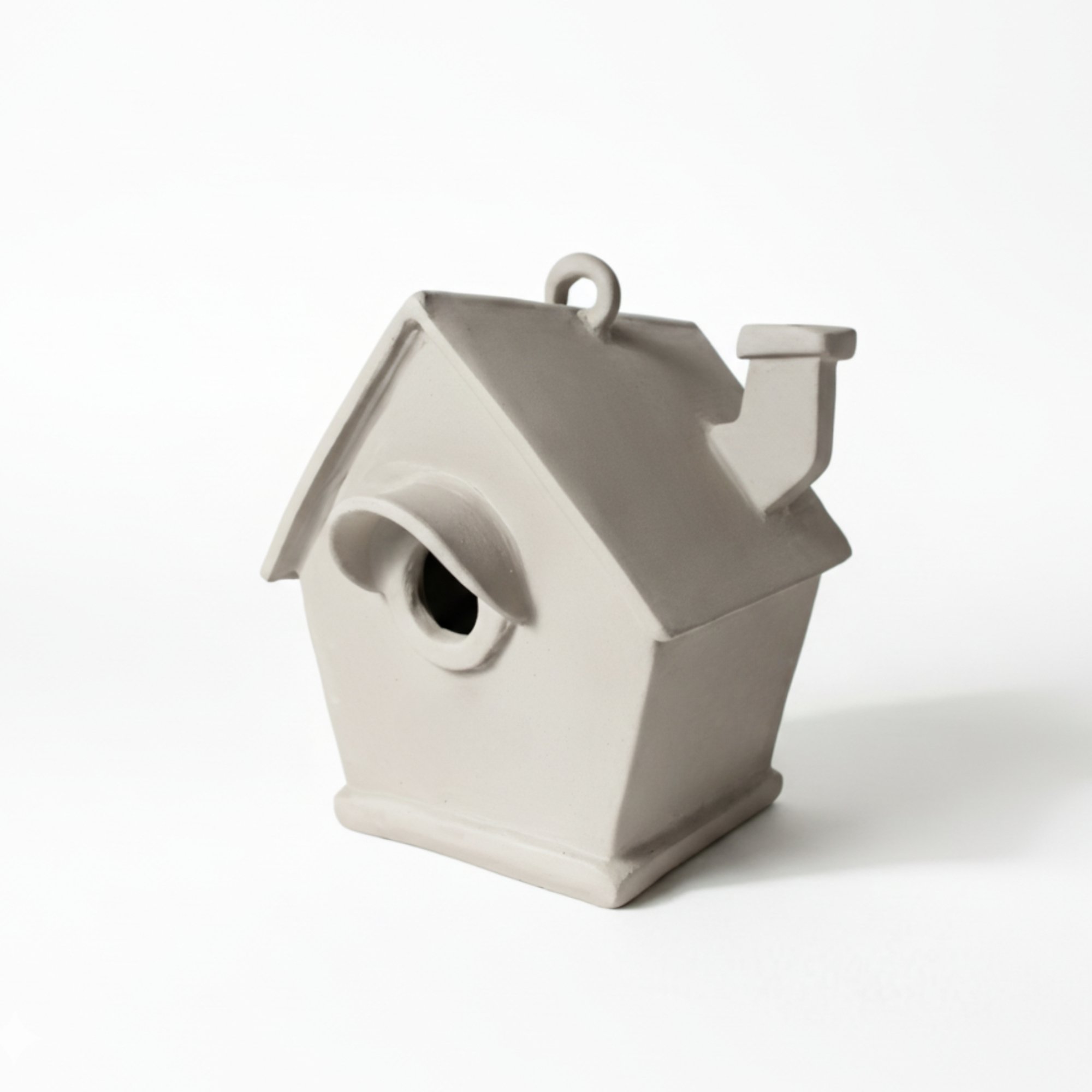 White handmade ceramic birdhouse with round entrance and chimney, inspired by pottery template and ceramic template concepts for slab pottery and beginner ceramics projects.
