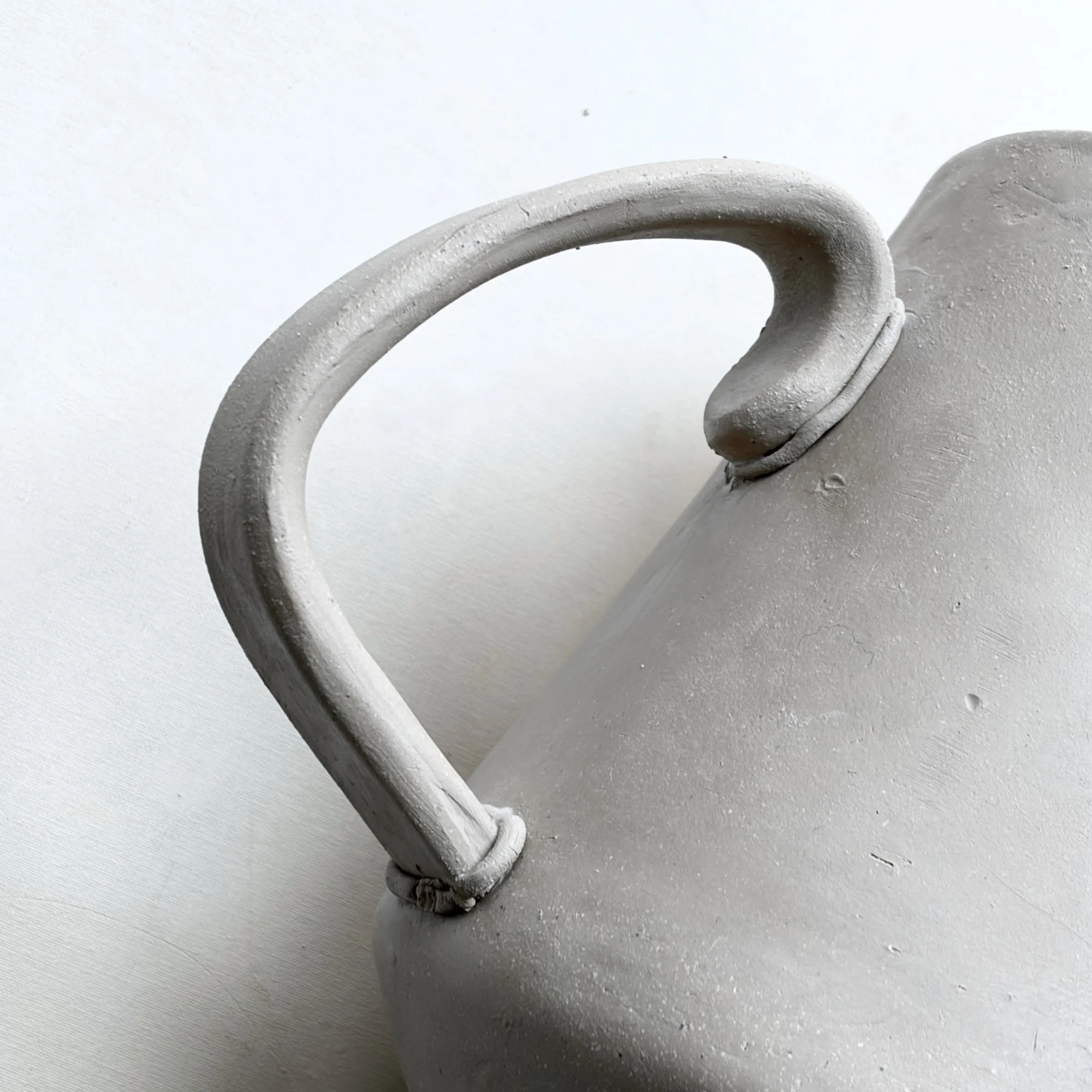 Adding a slab-built handle to a teapot using a pottery template.