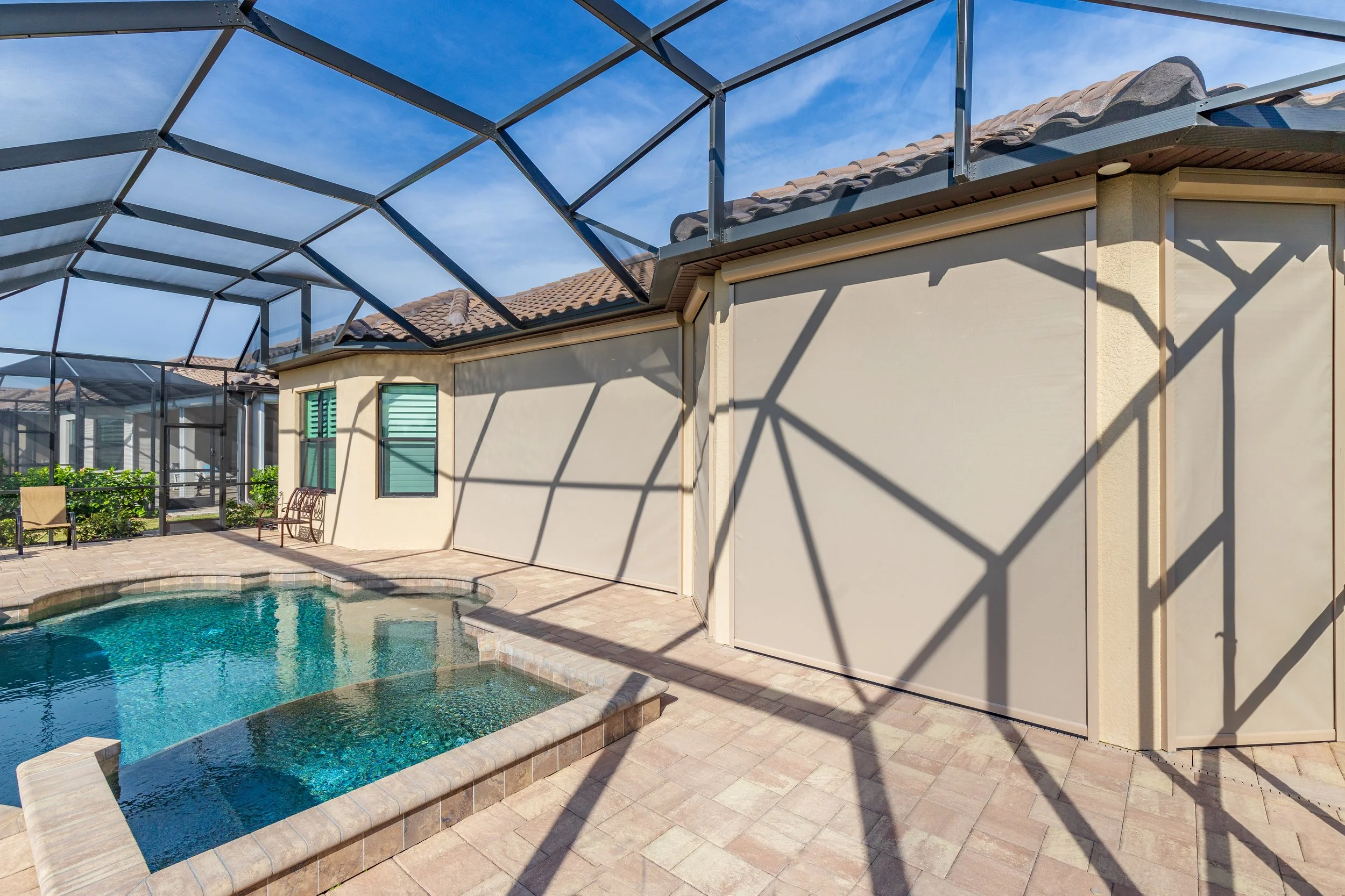Backyard with swimming pool, screened enclosure, and house wall with two windows and a door.