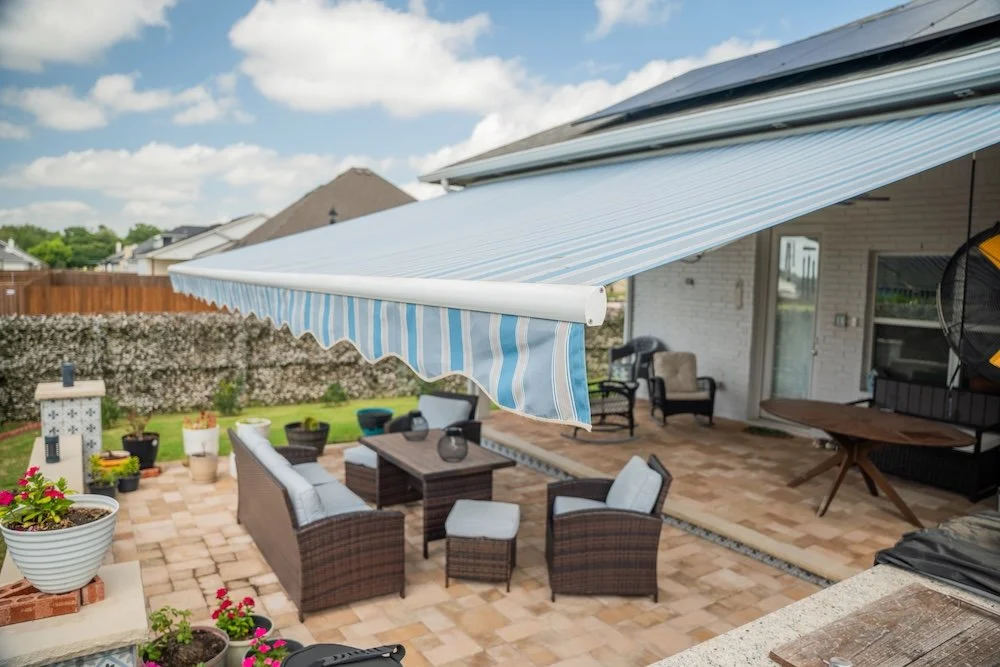 Blue striped retractable awning. Open over a paver patio in Florida. Lounge furniture on the patio.