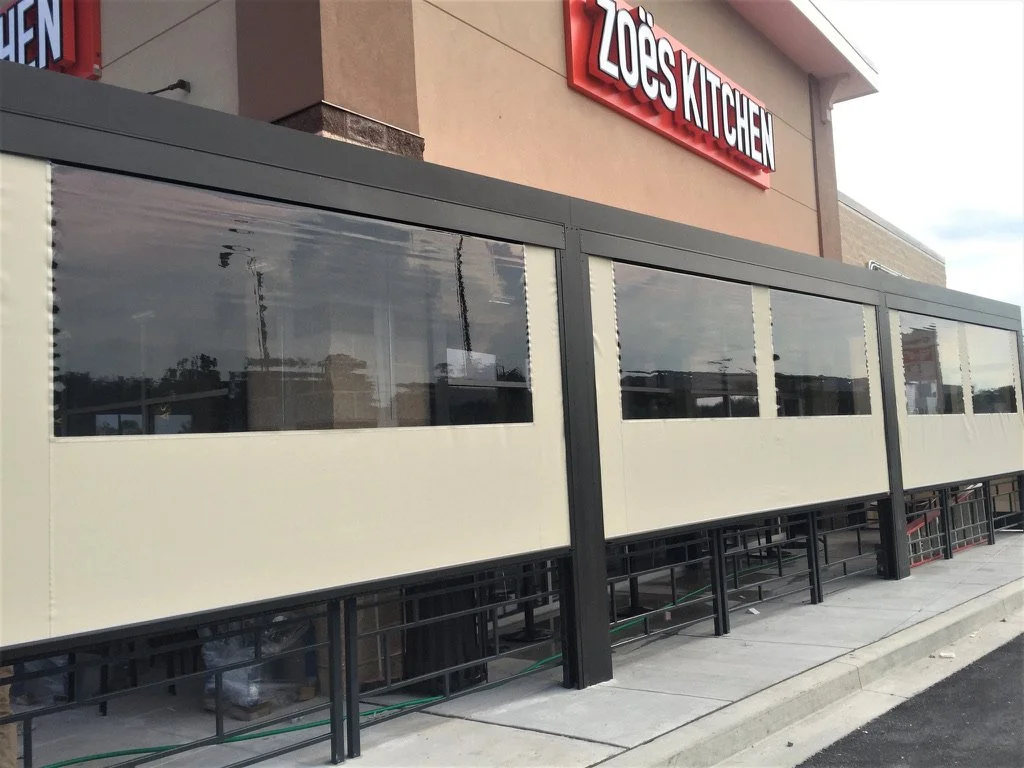 Exterior of Zoes Kitchen restaurant with a covered outdoor seating area.