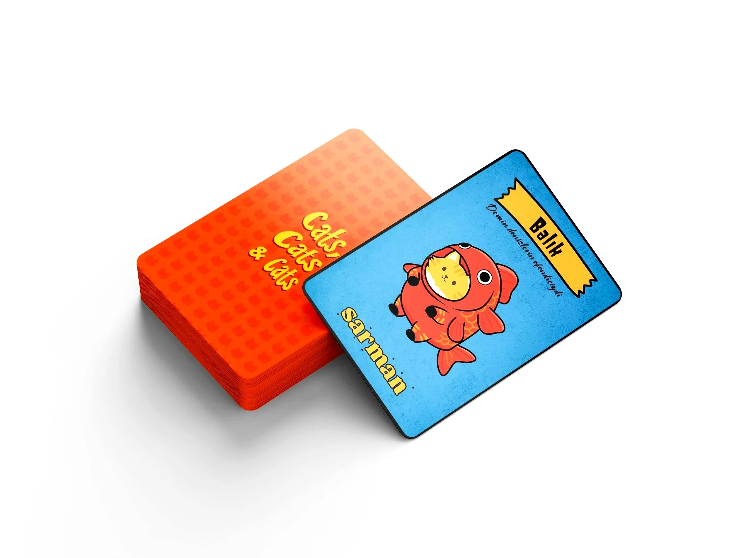 Bir yengeç şeklinde tasarlanmış ve bir kedi yüzü olan kart, mavi zemin üzerinde ve üzerinde İngilizce yazılmış 'Büyük', 'Değiştirebilir, Çalışabilir' ve 'Yemek' kelimeleri bulunuyor. Ayrıca, yanında kırmızı ve turuncu renklerde, 'Cats, Cats & Cats' yazılı başka bir kart yığılmış durumda.