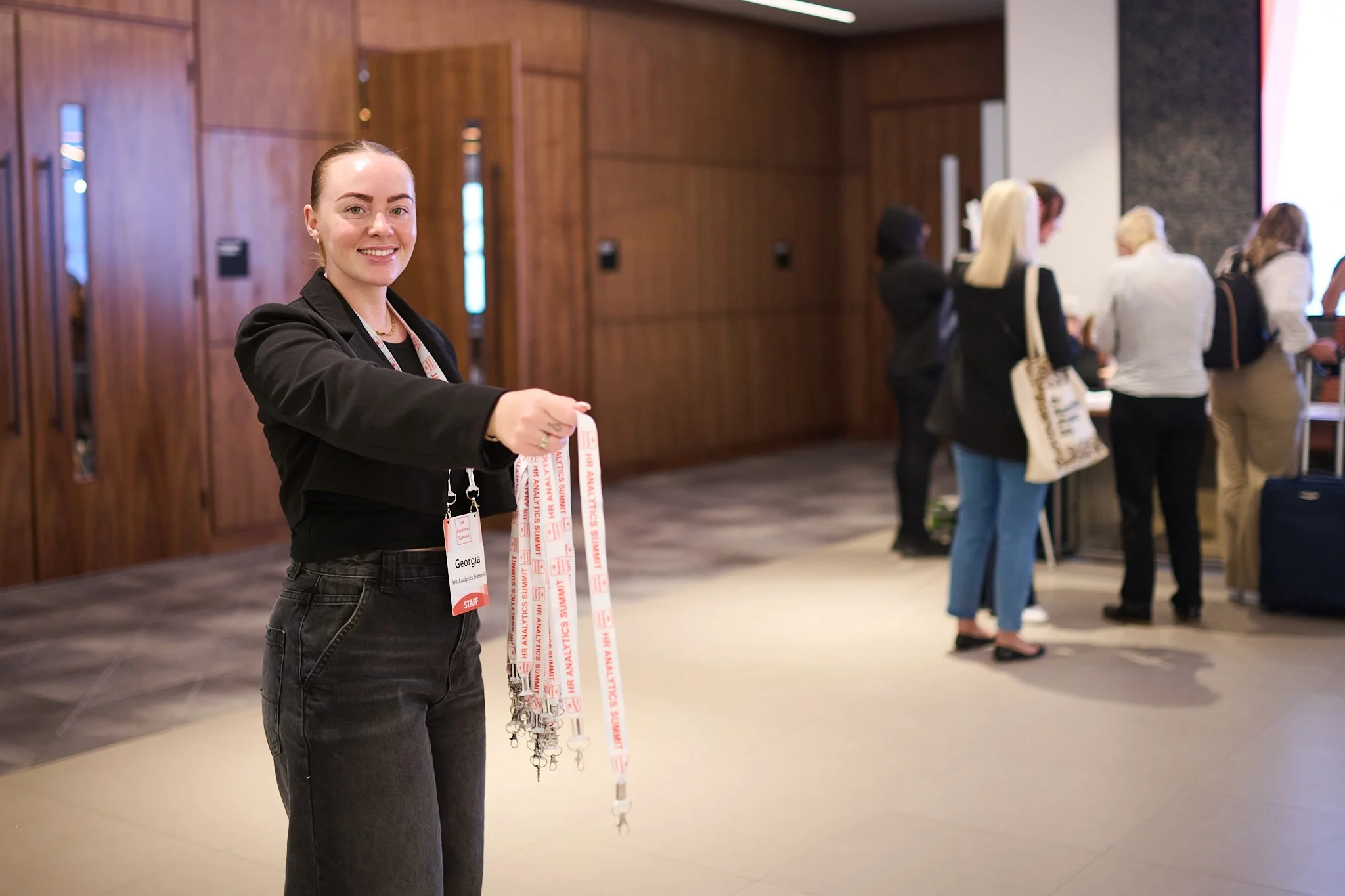 A person holding several lanyards in a conference hallway.