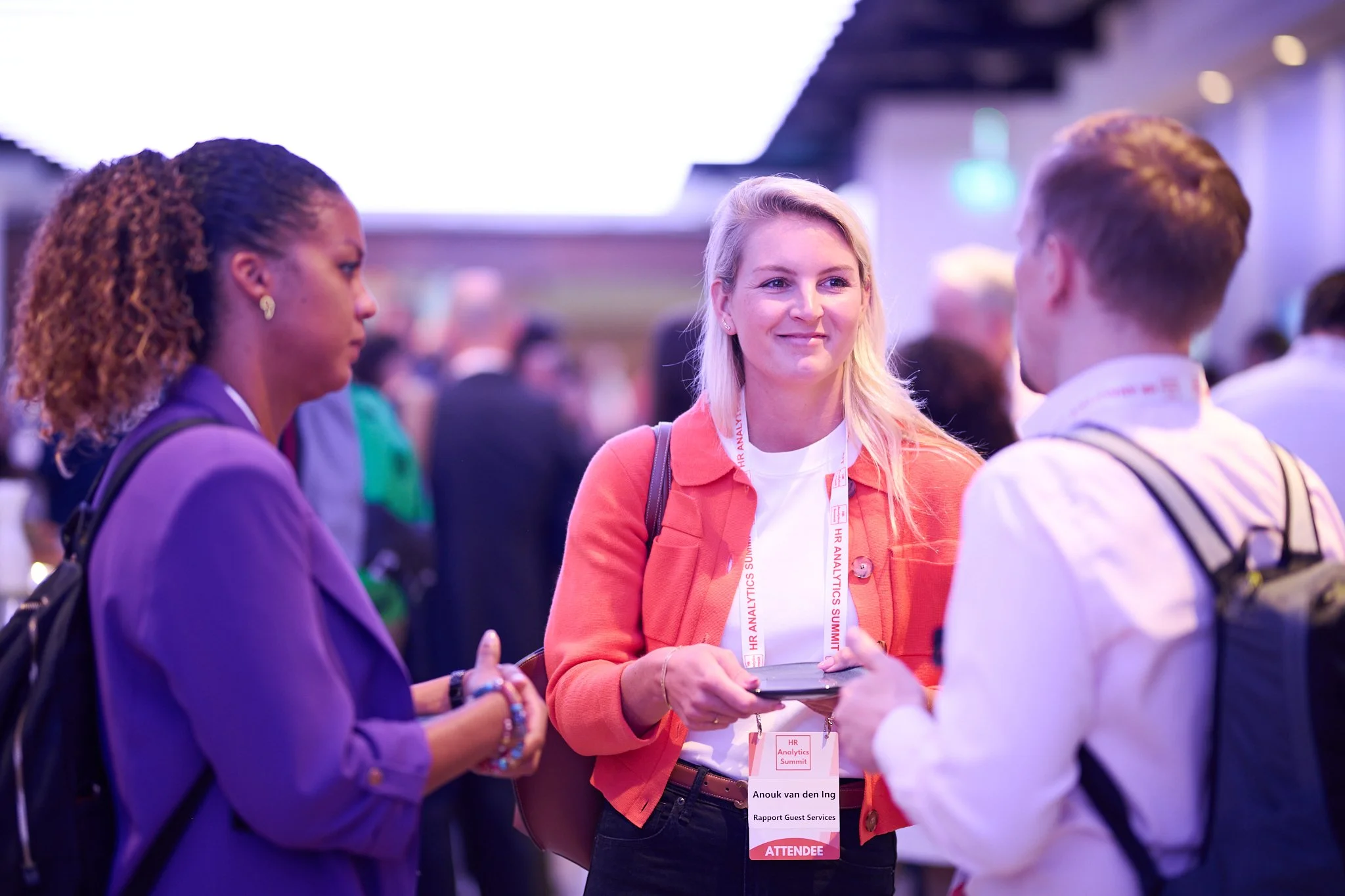 People at a conference chatting, wearing name badges.