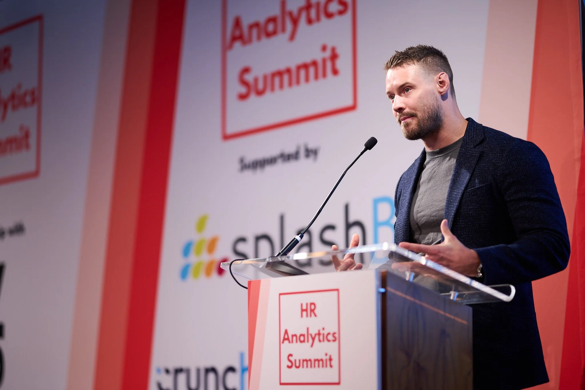 A man speaking at a podium during the HR Analytics Summit, supported by Splash.
