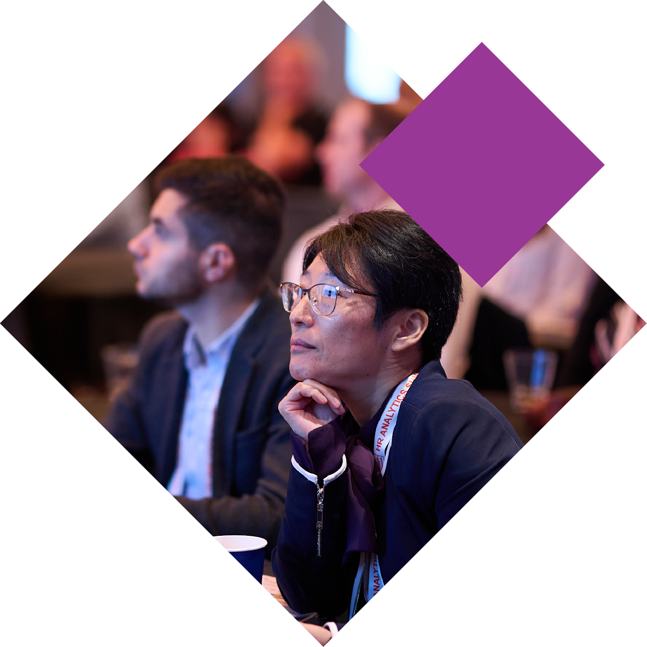 People attentively listening to a presentation at a conference, seated in an audience setting.