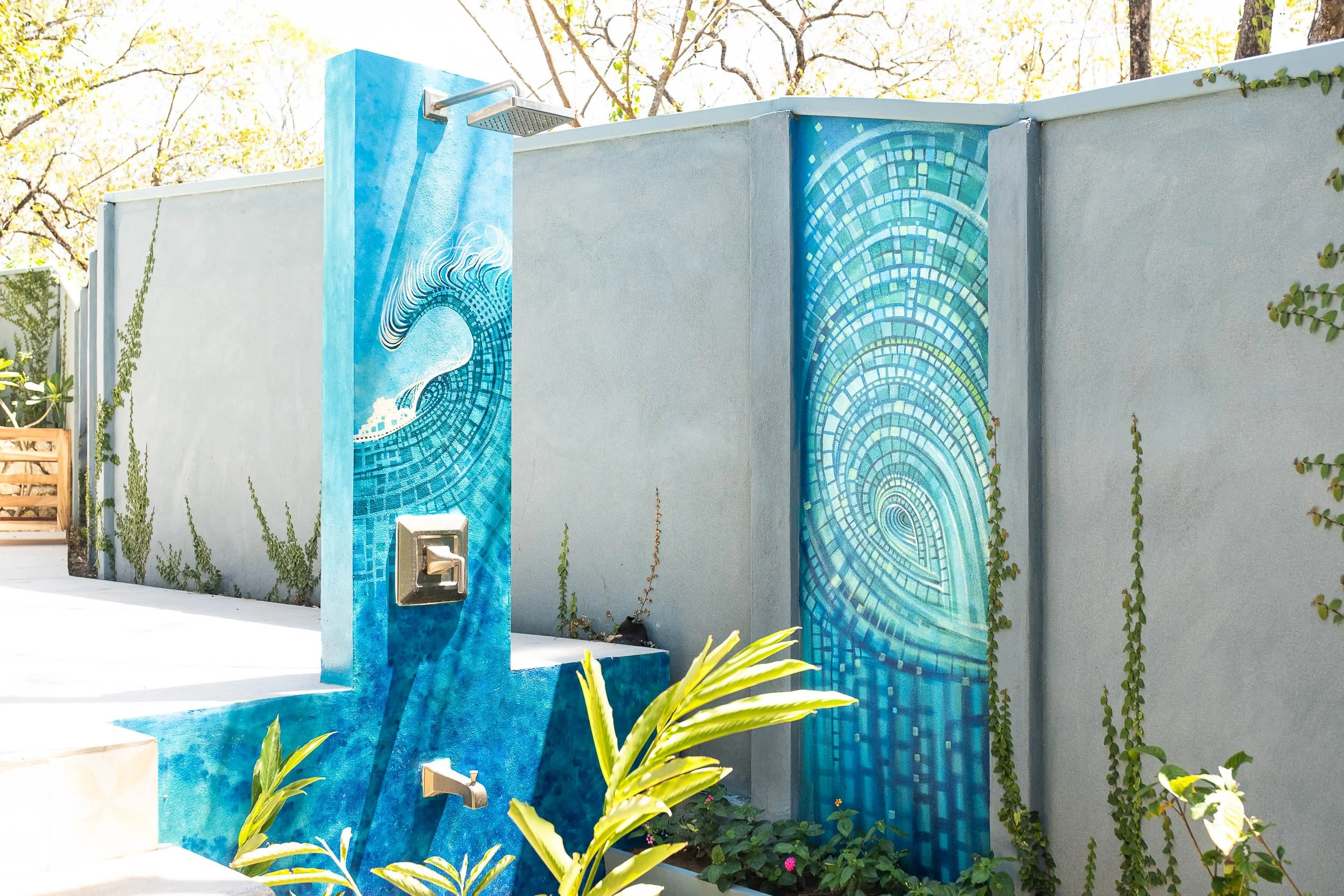 Outdoor water feature with a blue mosaic wave design on a wall and fountain