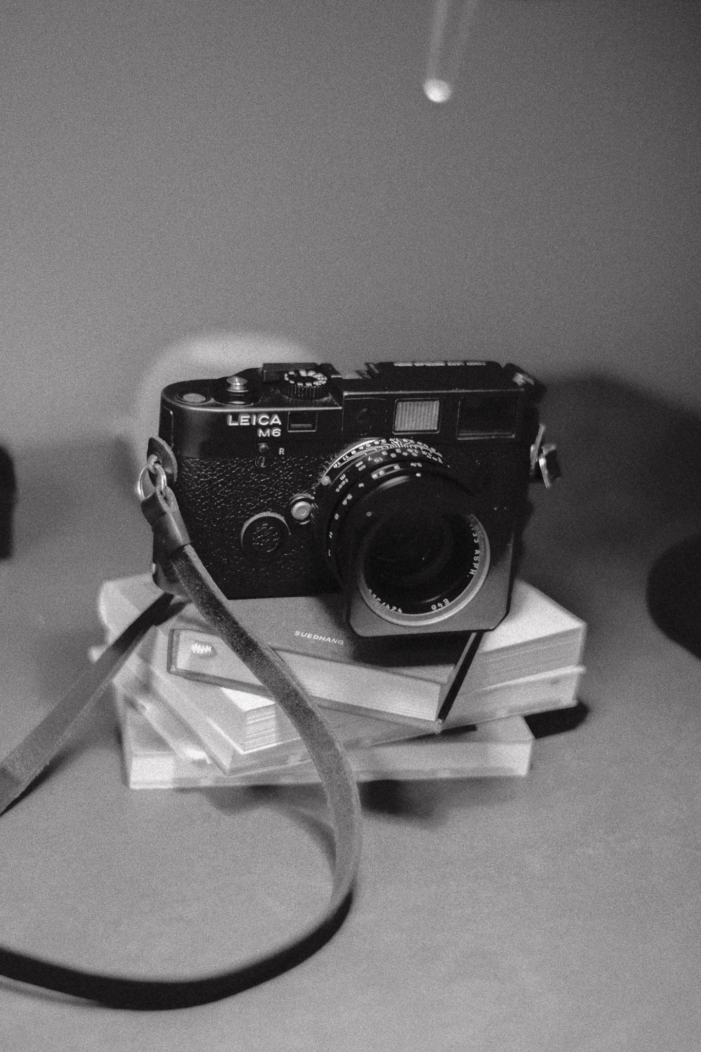 Fotografia in bianco e nero di una fotocamera Leica M6 appoggiata su un mazzo di libri.