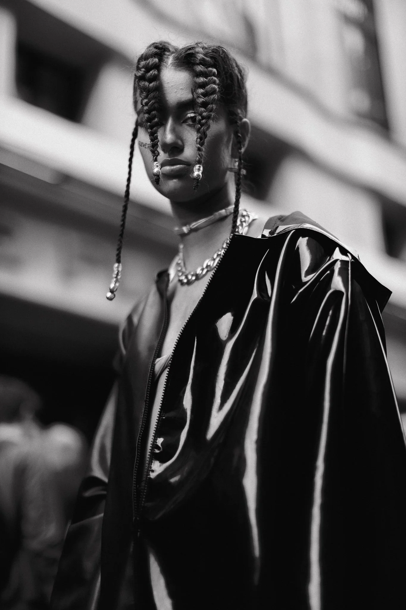 Ragazza con treccine, gioielli e giacca di pelle nera in ambiente urbano