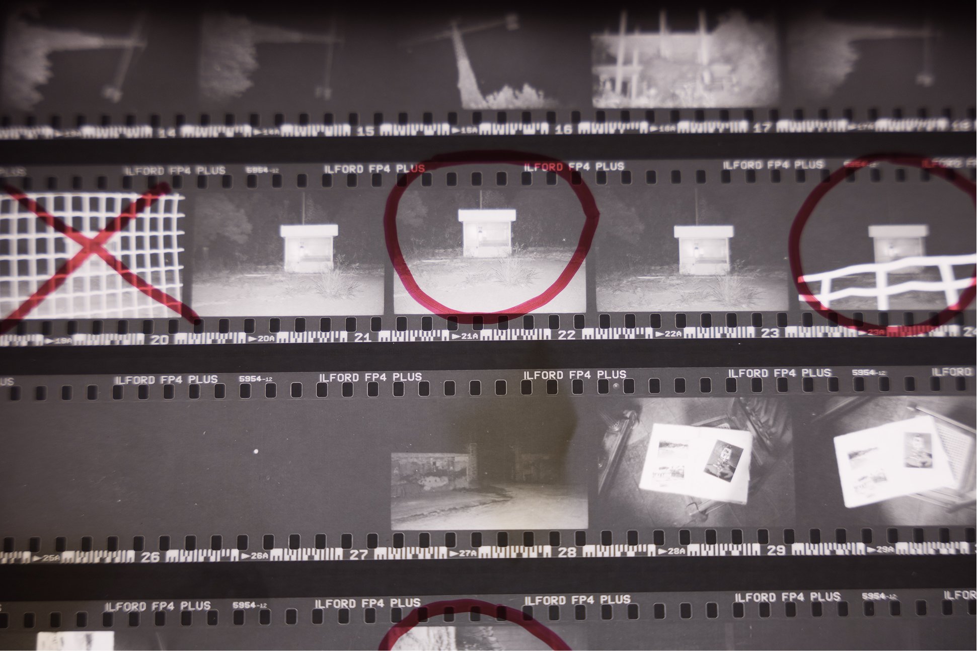 Una bobina di pellicola fotografica con alcune immagini in bianco e nero e cerchi rossi disegnati sulla pellicola.