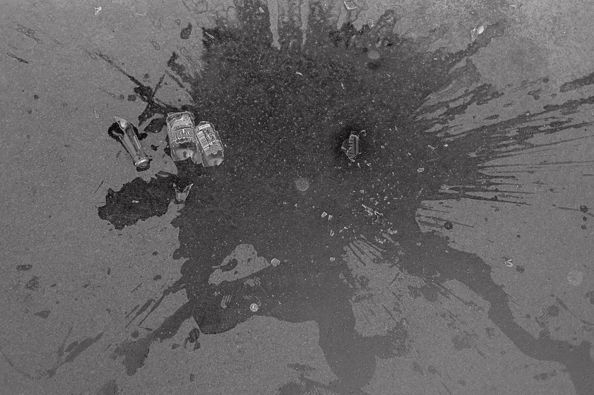 Macchie di olio e bottiglie di plastica sul marciapiede.