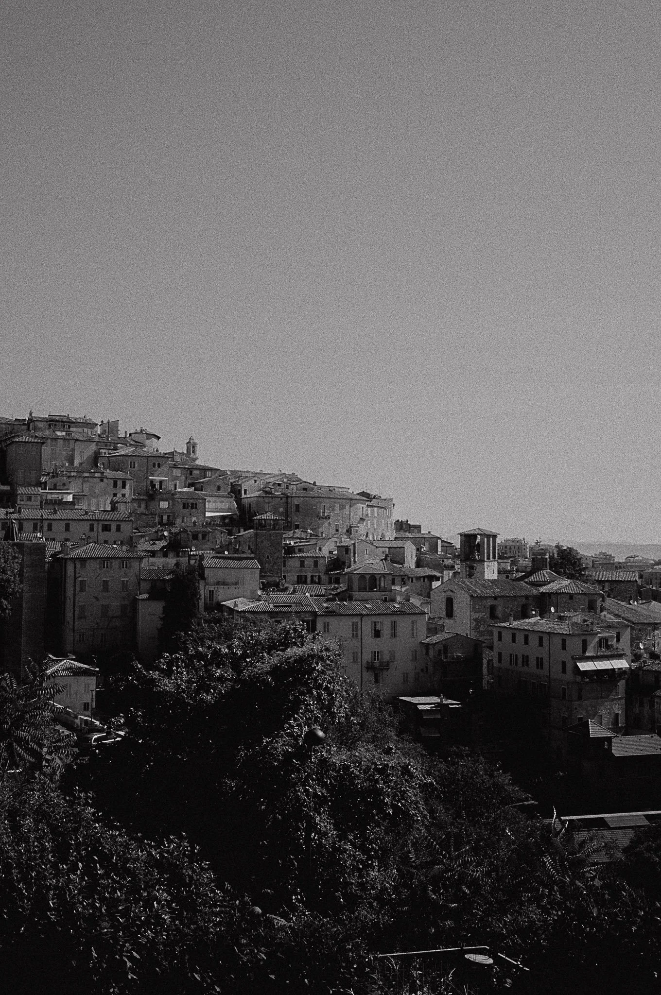Scorcio di un paesaggio urbano con edifici storici su una collina, vista dal basso, in bianco e nero.