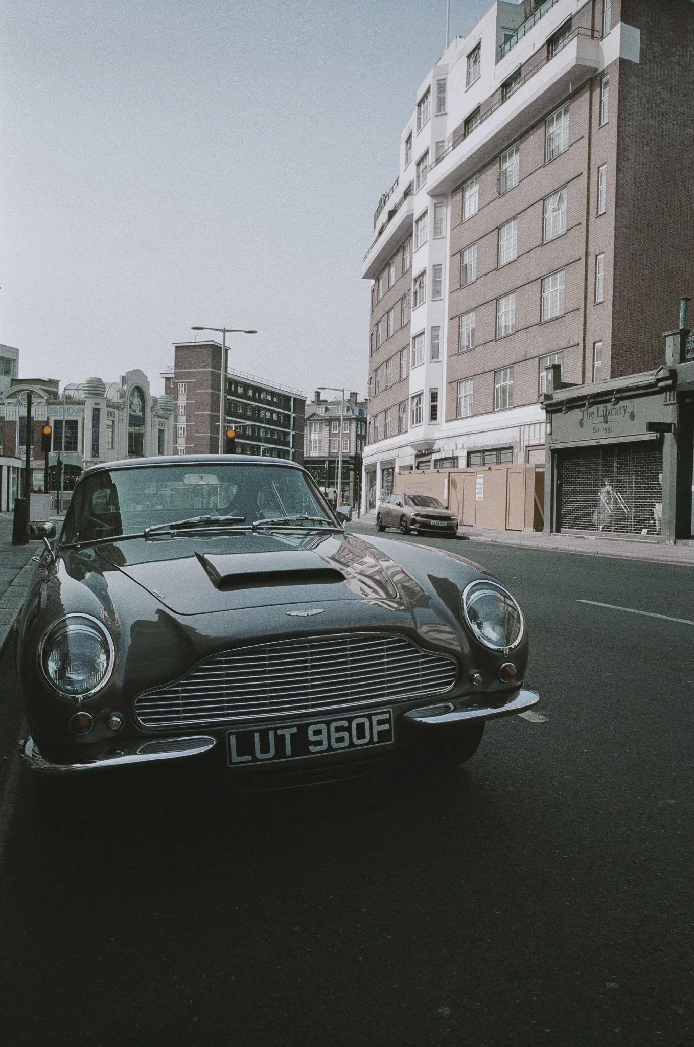 Automobile classica parcheggiata su strada in un'area urbana con edifici moderni sullo sfondo.