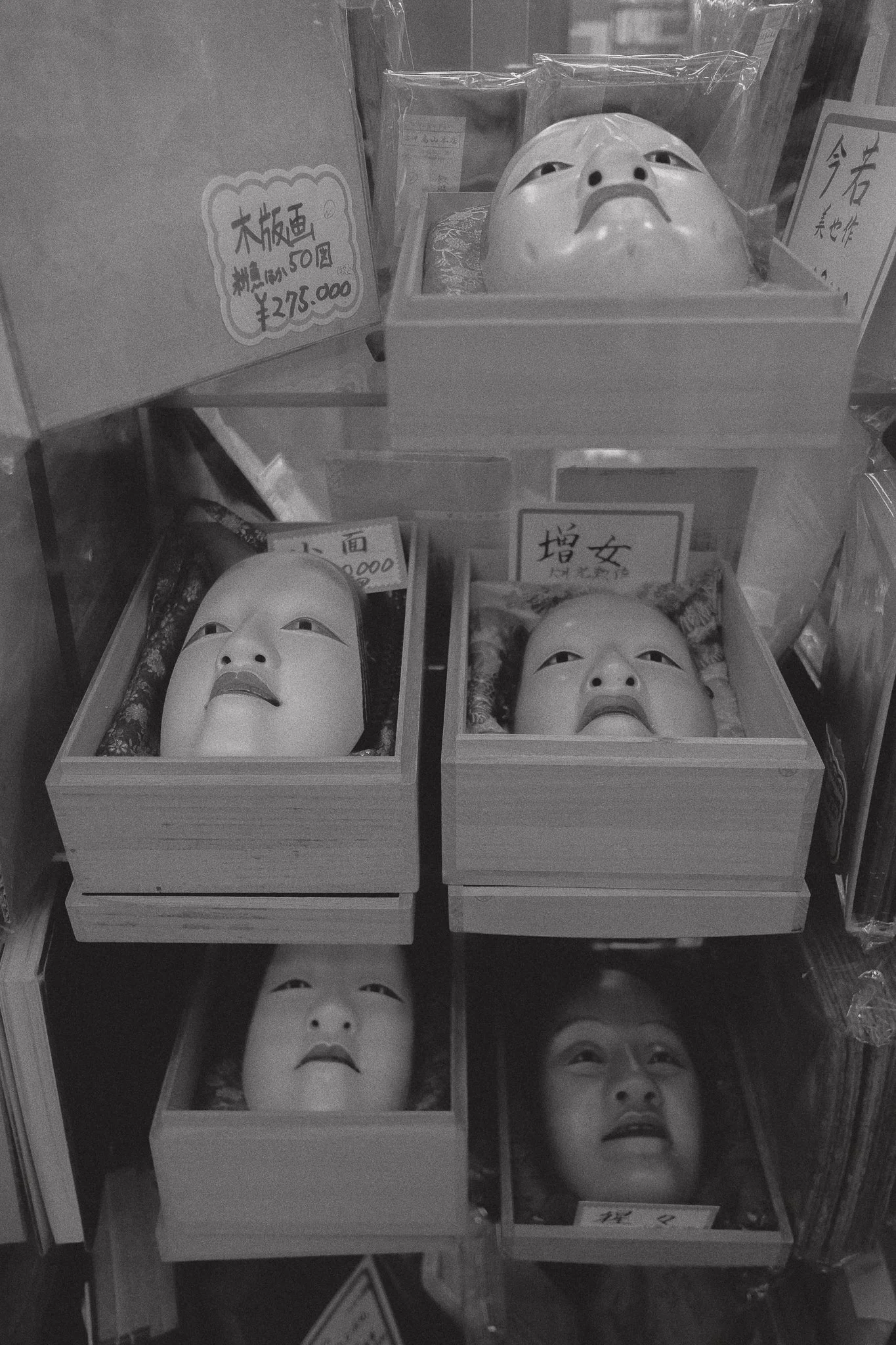 Maschere tradizionali giapponesi vintage esposte in scatole di legno.