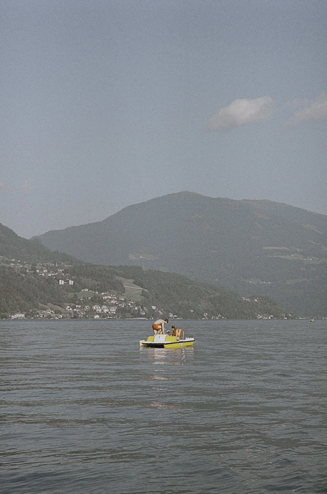 Due persone in una pedalò giallo su un lago tra le montagne