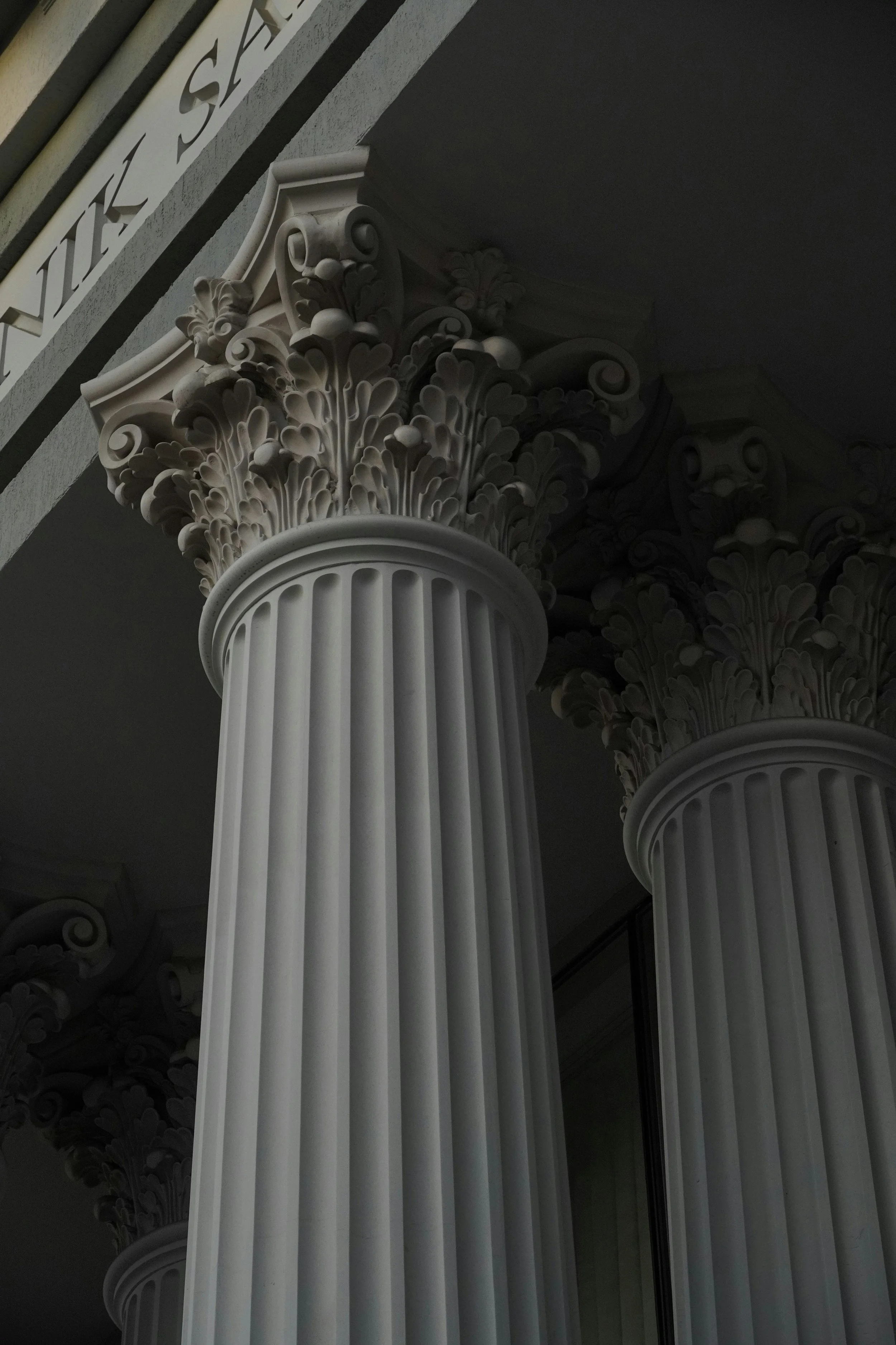 Close-up of classical style marble columns with ornate Corinthian capitals.