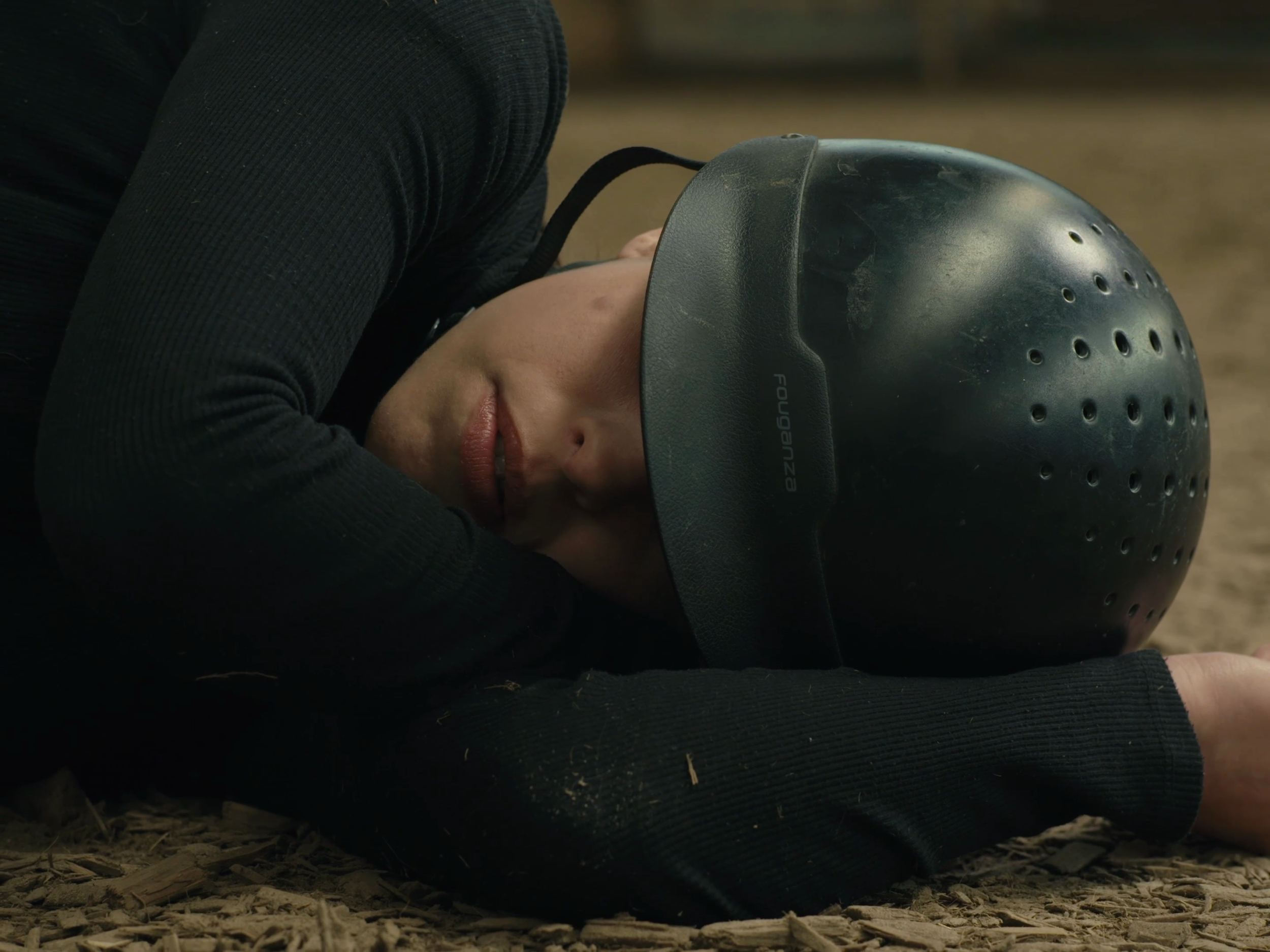 Une personne allongée par terre, portant un casque de vélo, avec une expression de tristesse ou de douleur.