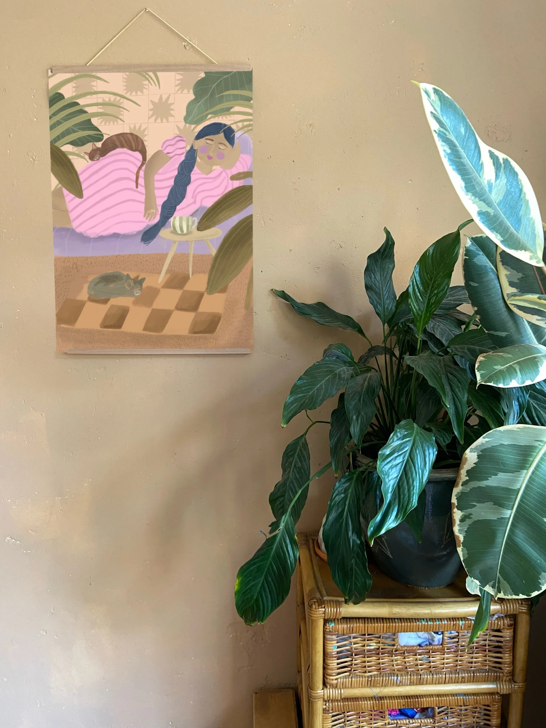 Bohemian art print in een stijlvol huis, de poster is in pastel kleuren zoals roze en lila en aardetinten, met tropische planten op de achtergrond.