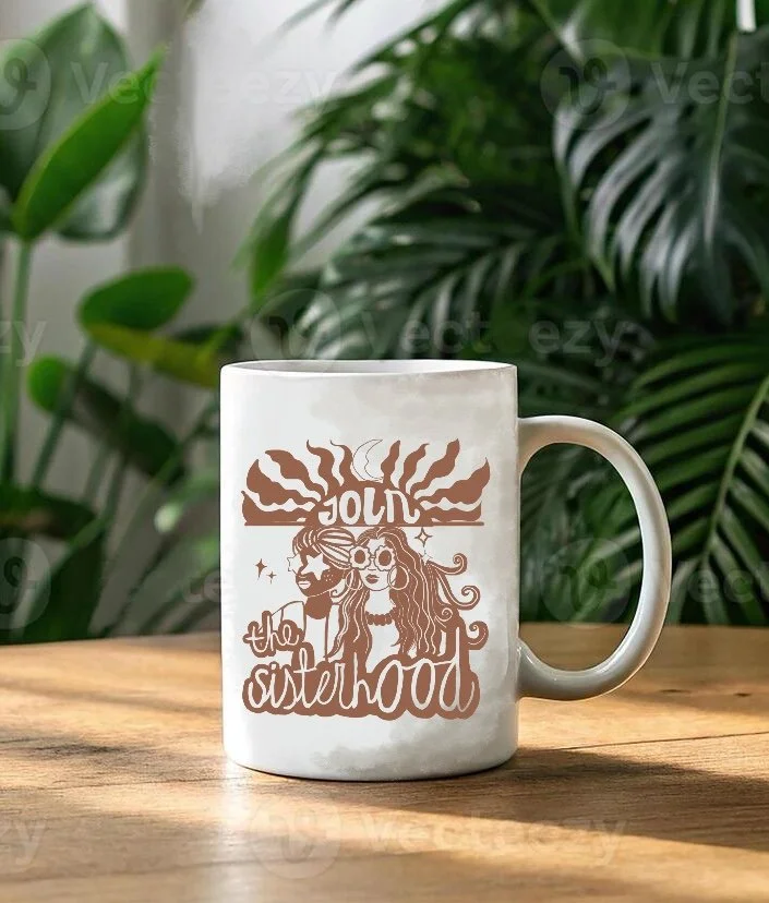 White mug with a brown illustration of a man and woman with flowing hair, sunglasses, and the words 'Jolly the Sisterhood' on a wooden surface, with green plants in the background.