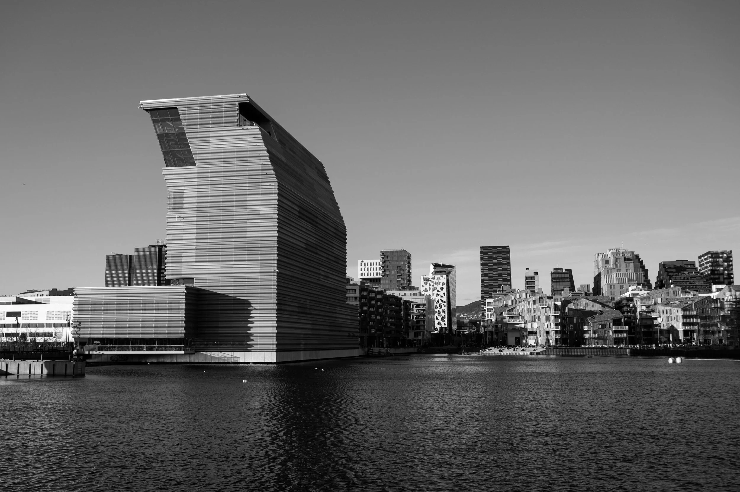 Svart/hvitt bilde av Oslos Skyline, med Munch museet i front.