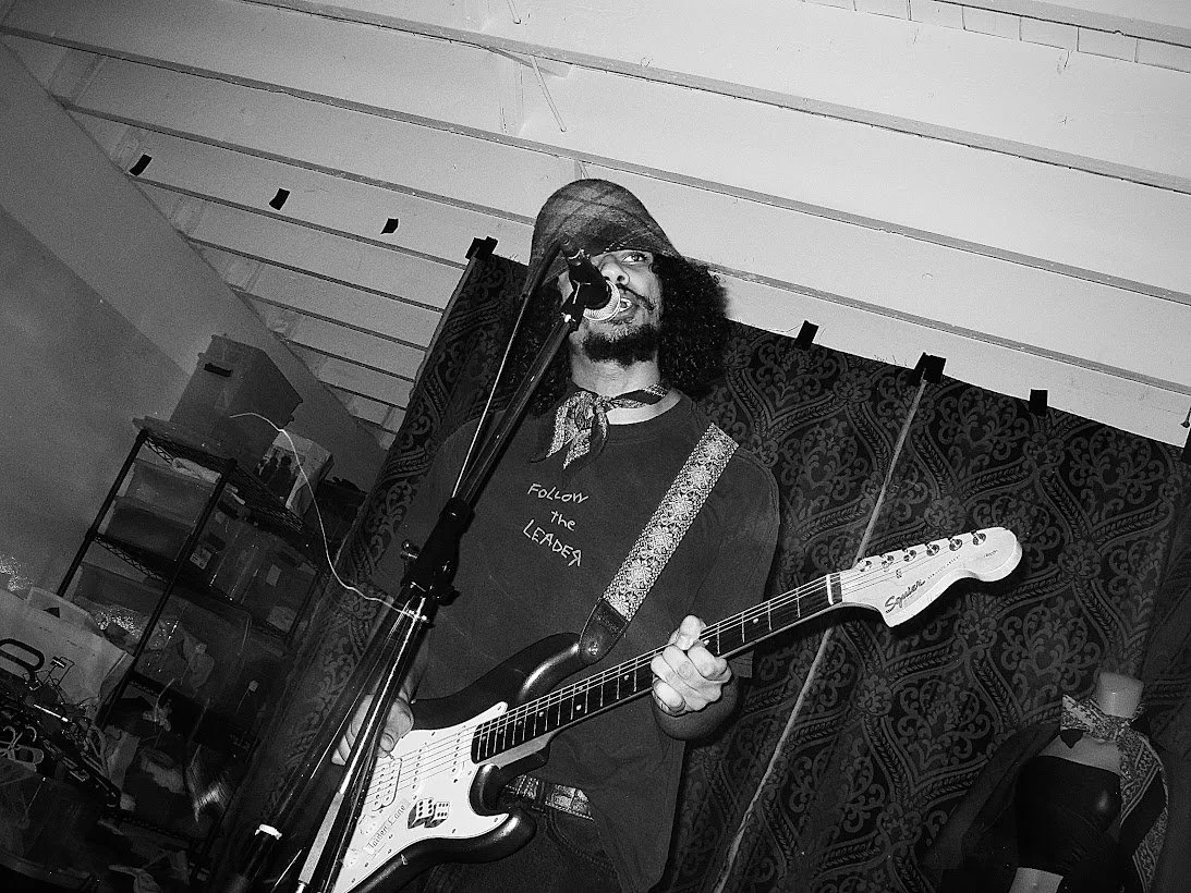 Man playing electric guitar singing into a microphone live on stage.