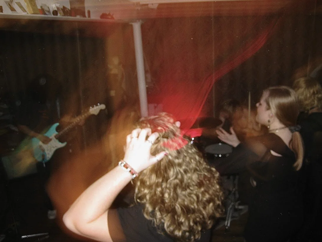 Blurry shot from behind the crowd, Maiden Lane frontman's teal guitar stands out through the blur.