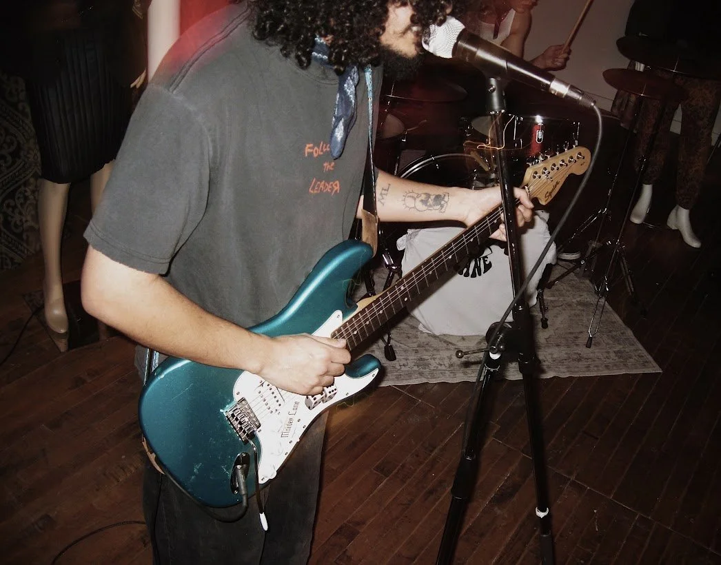 Maiden Lane frontman singing into microphone and playing electric guitar.