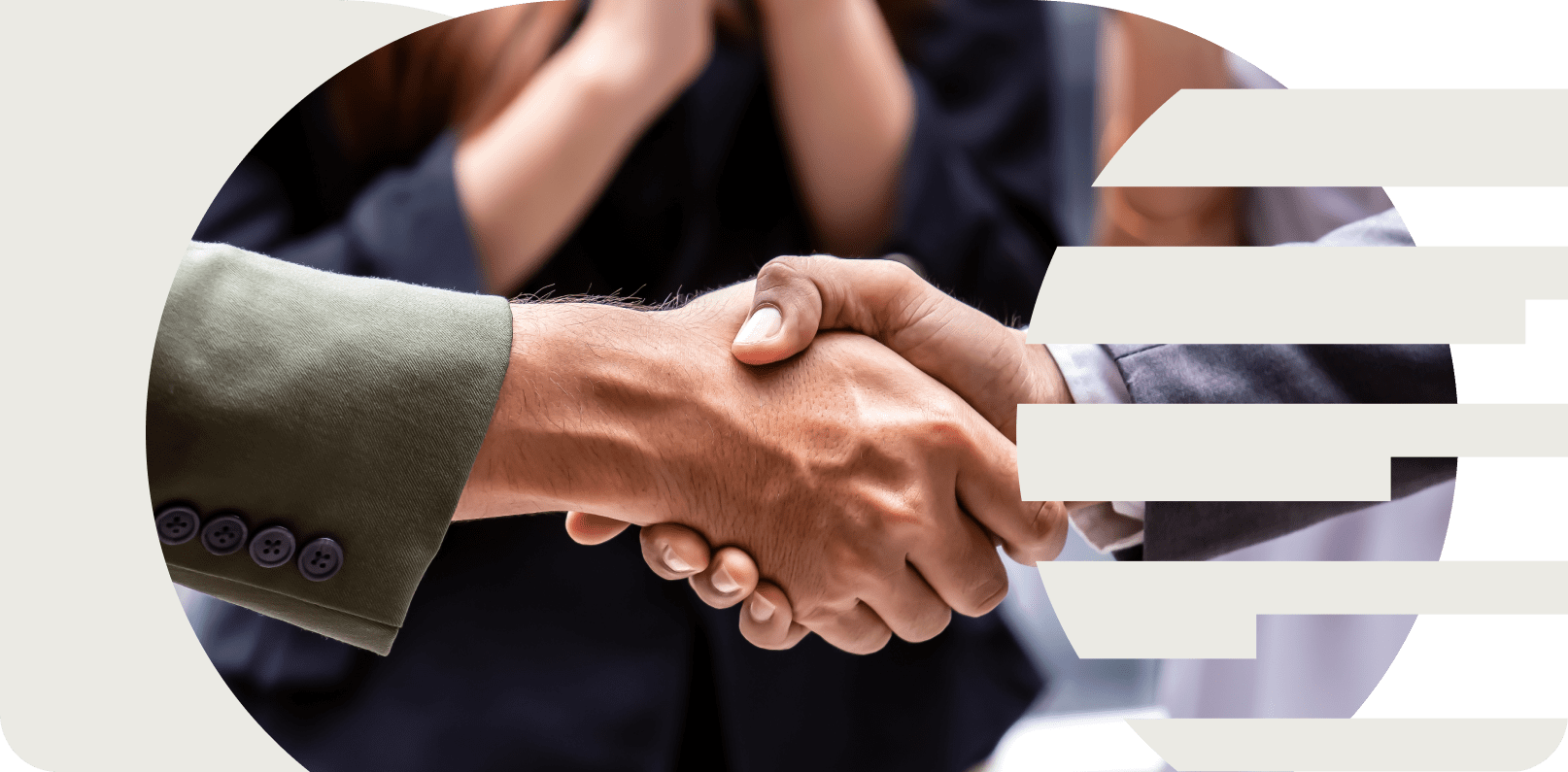 Two people shaking hands in a business setting, with a person in professional attire and a blurred person in the background.