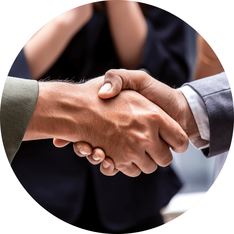 Close-up of two people shaking hands in a professional setting, with a woman in the background.