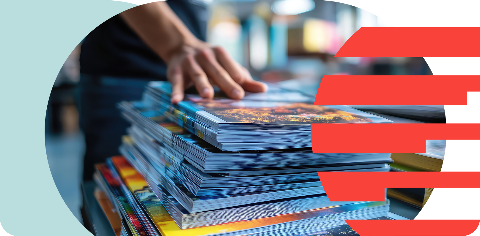 Stacks of colorful brochures or magazines on a table with a person's hand flipping through them.