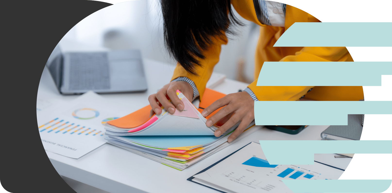 Person flipping through a thick stack of colorful files and charts on a white desk, with a telephone and printed documents around.