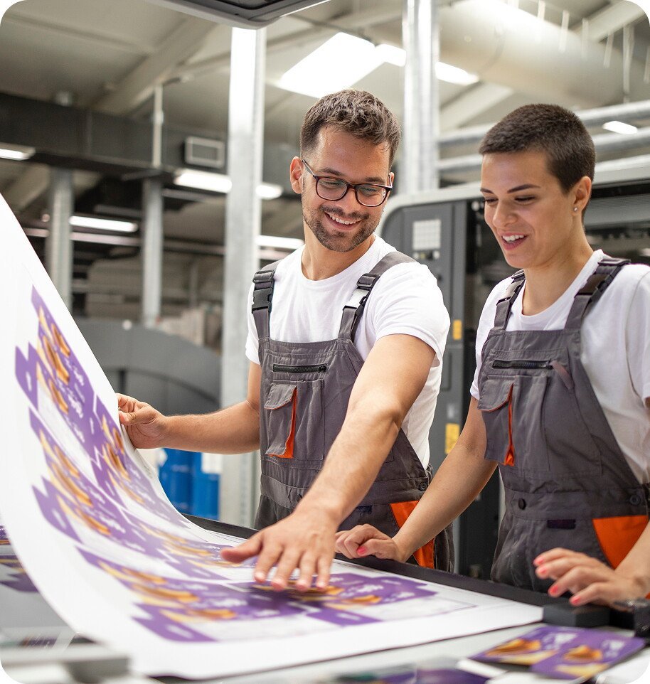 two people reviewing print job on large sheet of paper in a print shop setting