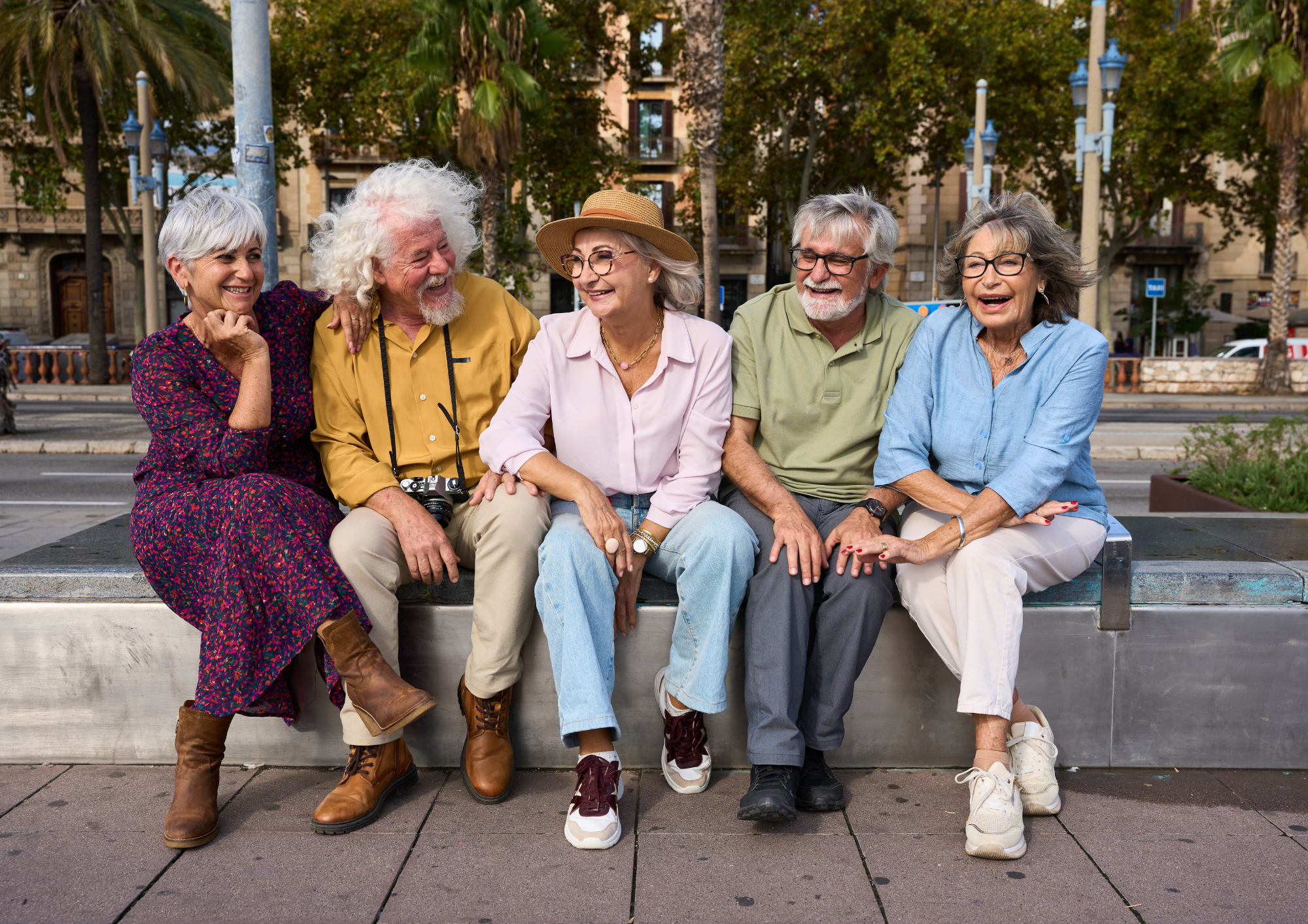 Cinq seniors assis sur un banc en ville, souriant et riant ensemble.