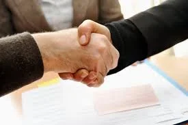 Deux personnes se serrent la main, symbolisant un accord ou une entente.