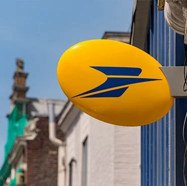Ballon publicitaire jaune avec logo bleu, suspendu à l'extérieur d'un bâtiment.