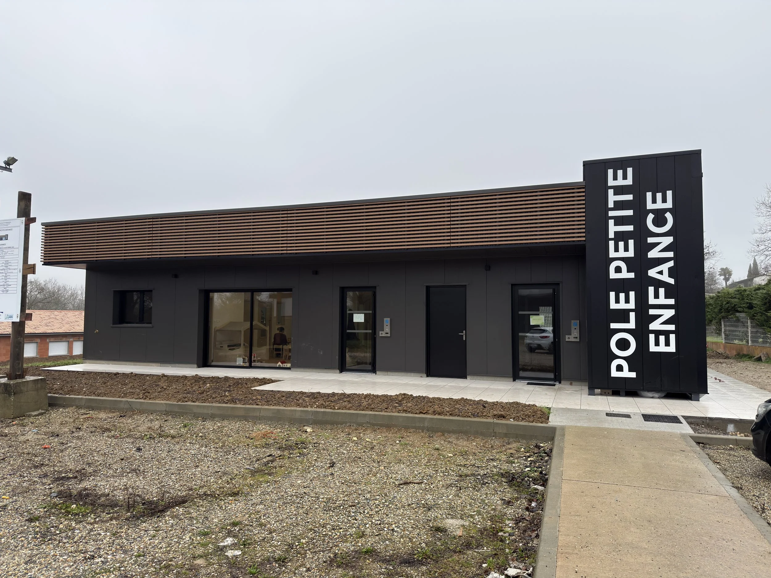 Bâtiment moderne avec enseigne 'Pôle Petite Enfance' sur le côté.