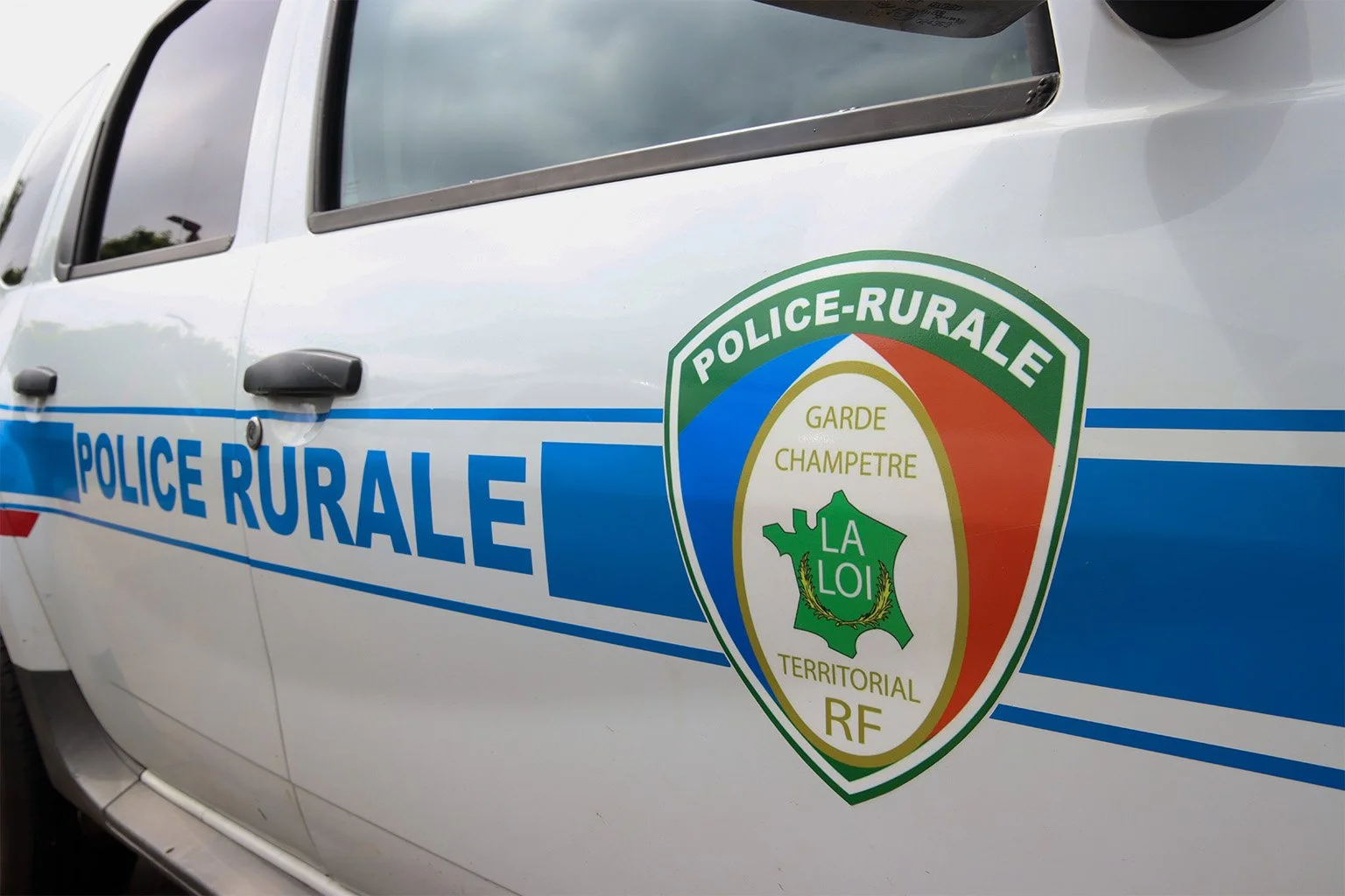 Voiture de police avec le logo de la police rurale française sur la porte.