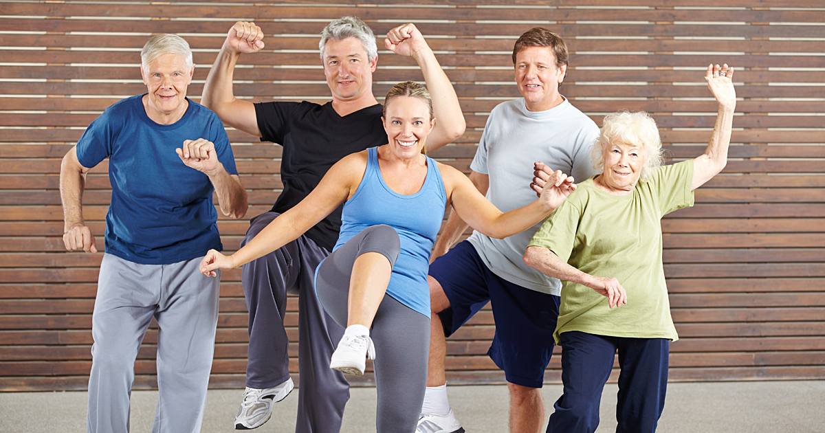 groupe de personnes âgées en activité physique, faisant de l'exercice ensemble en salle, souriantes et motivées