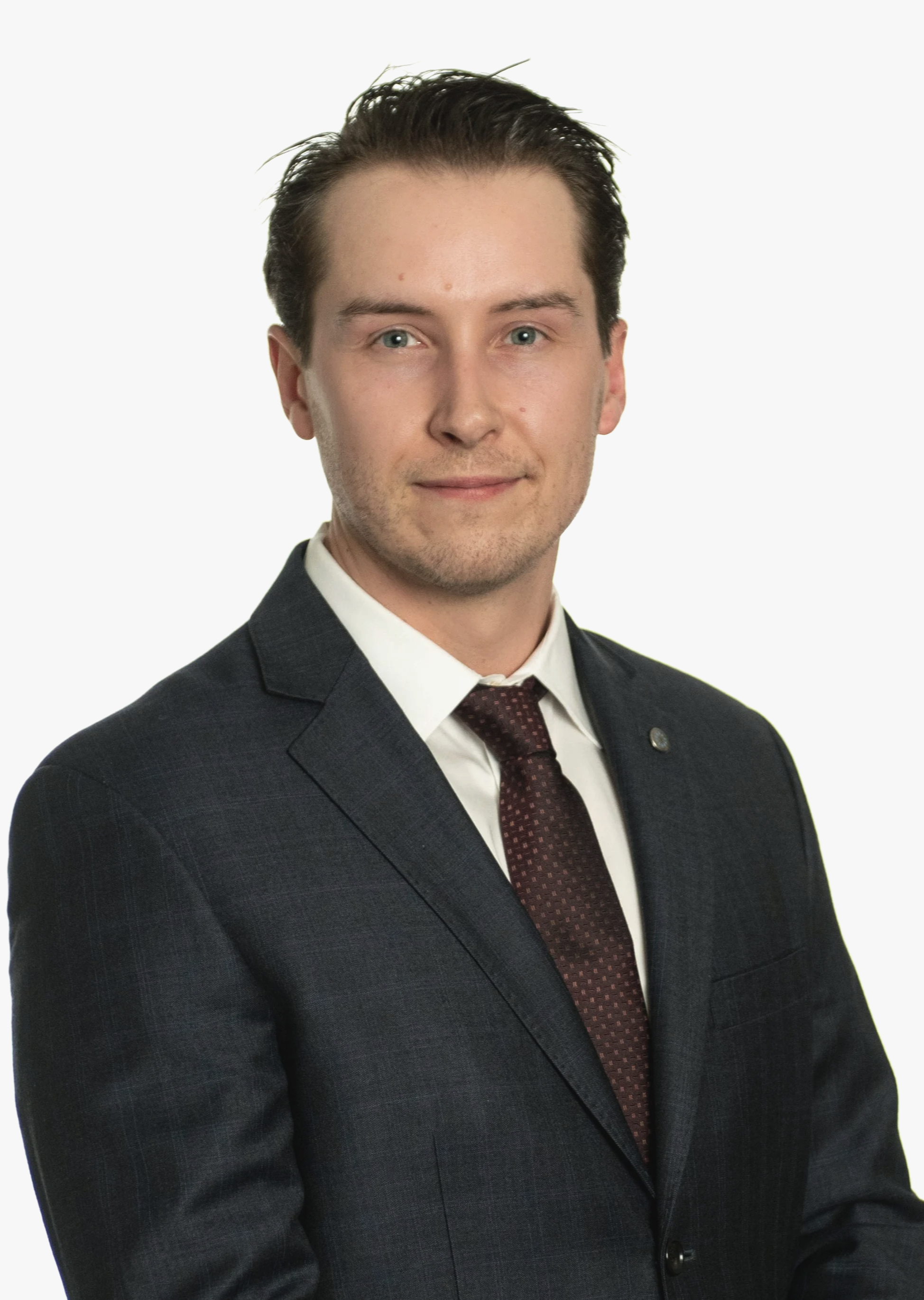 A young man in a dark suit, white shirt, and patterned tie, posing against a plain white background.