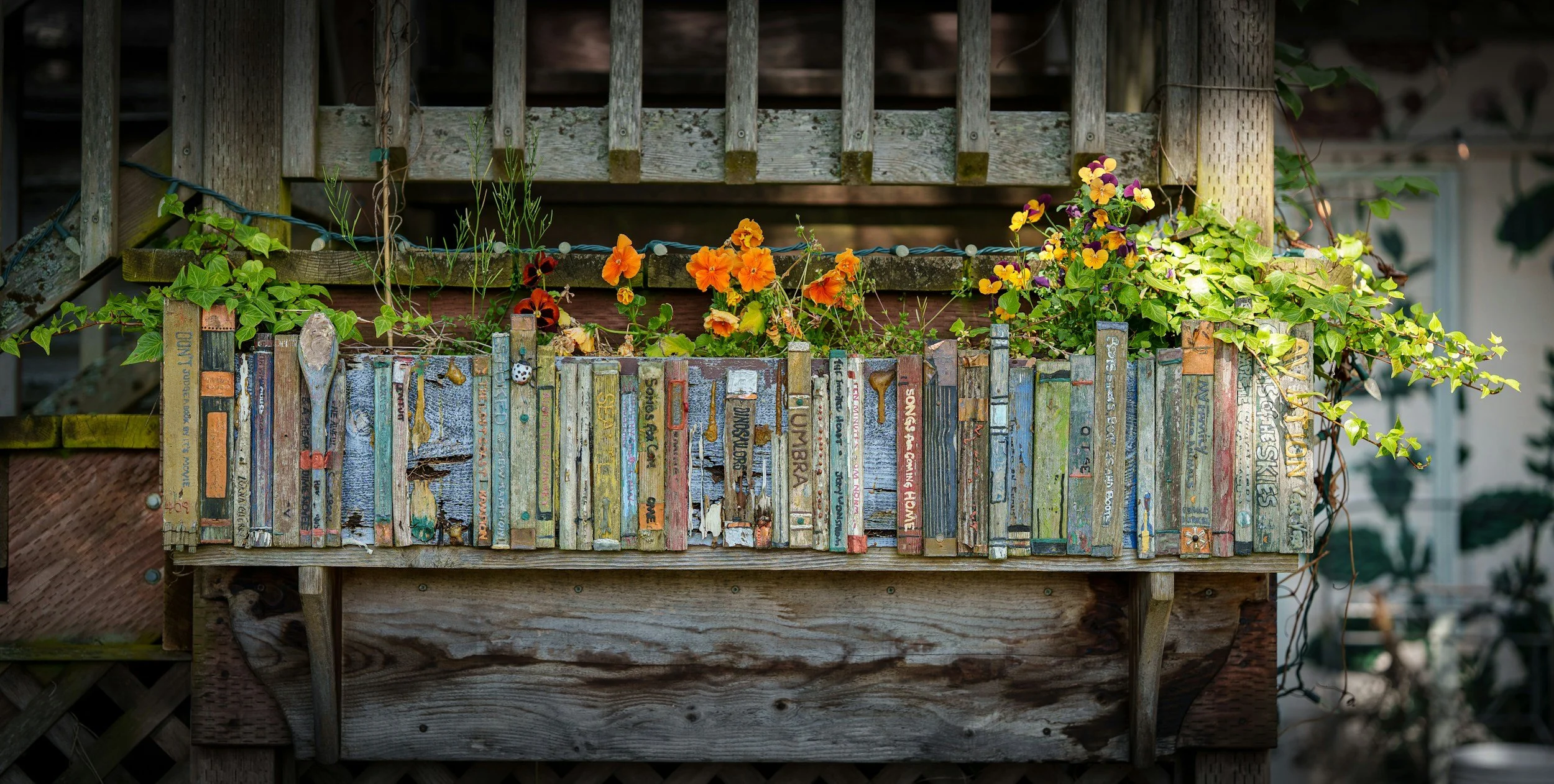 rustic shelf holding several books with flowers growing out of the top