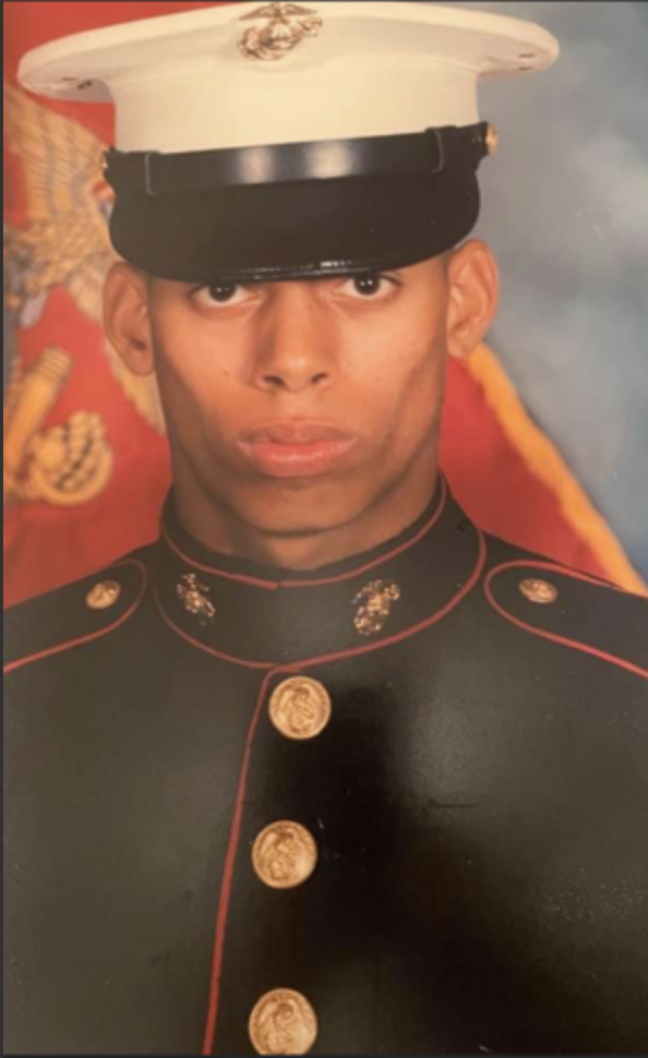Portrait of a young Marine in dress uniform with a White Marine Corps hat and medals.