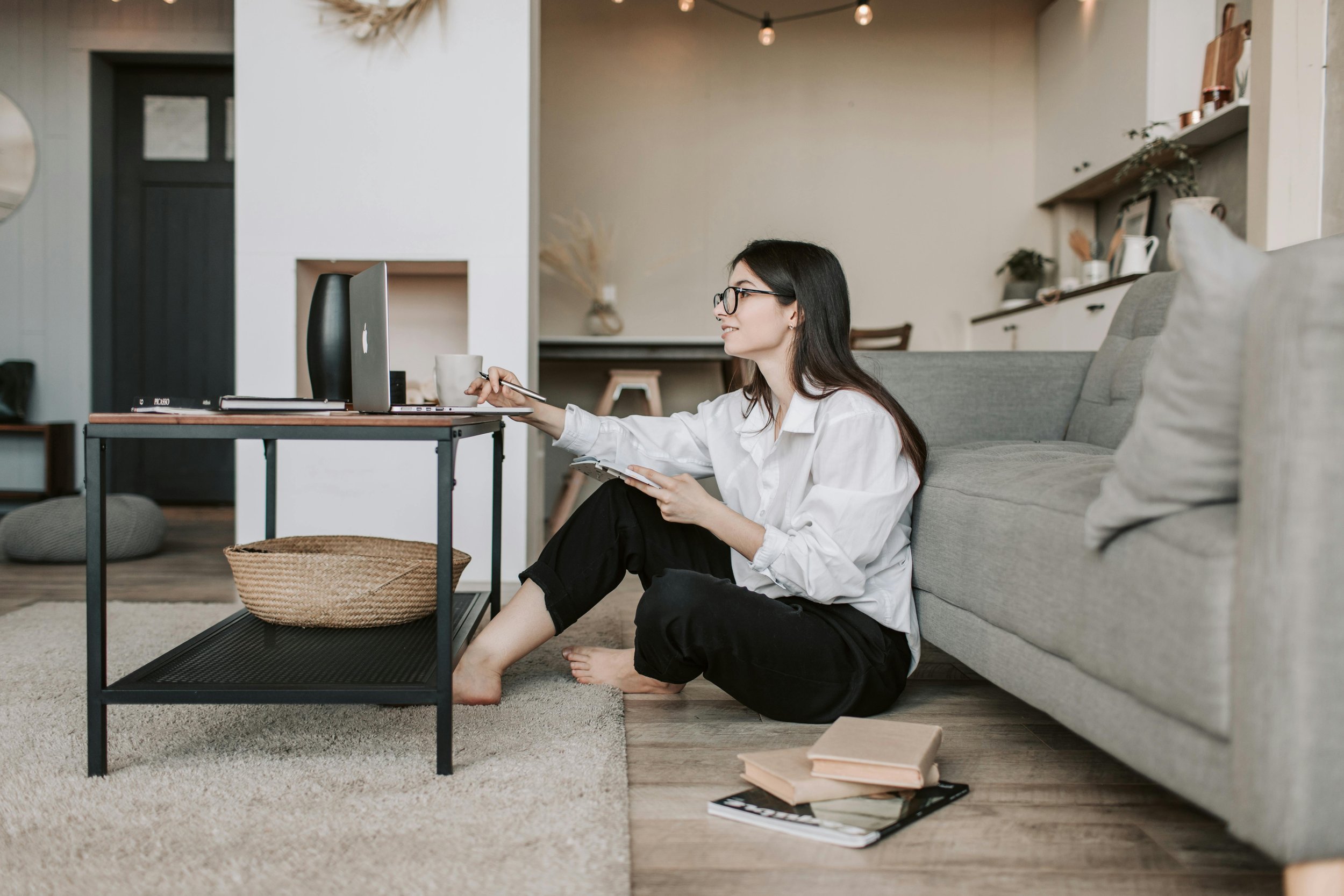 A woman sitting on the floor working on her laptop, reflecting focus, ambition, and the pressures of high achievement.