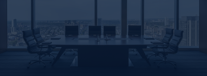 Empty conference room with a long table, six chairs, and large windows showing a city skyline.