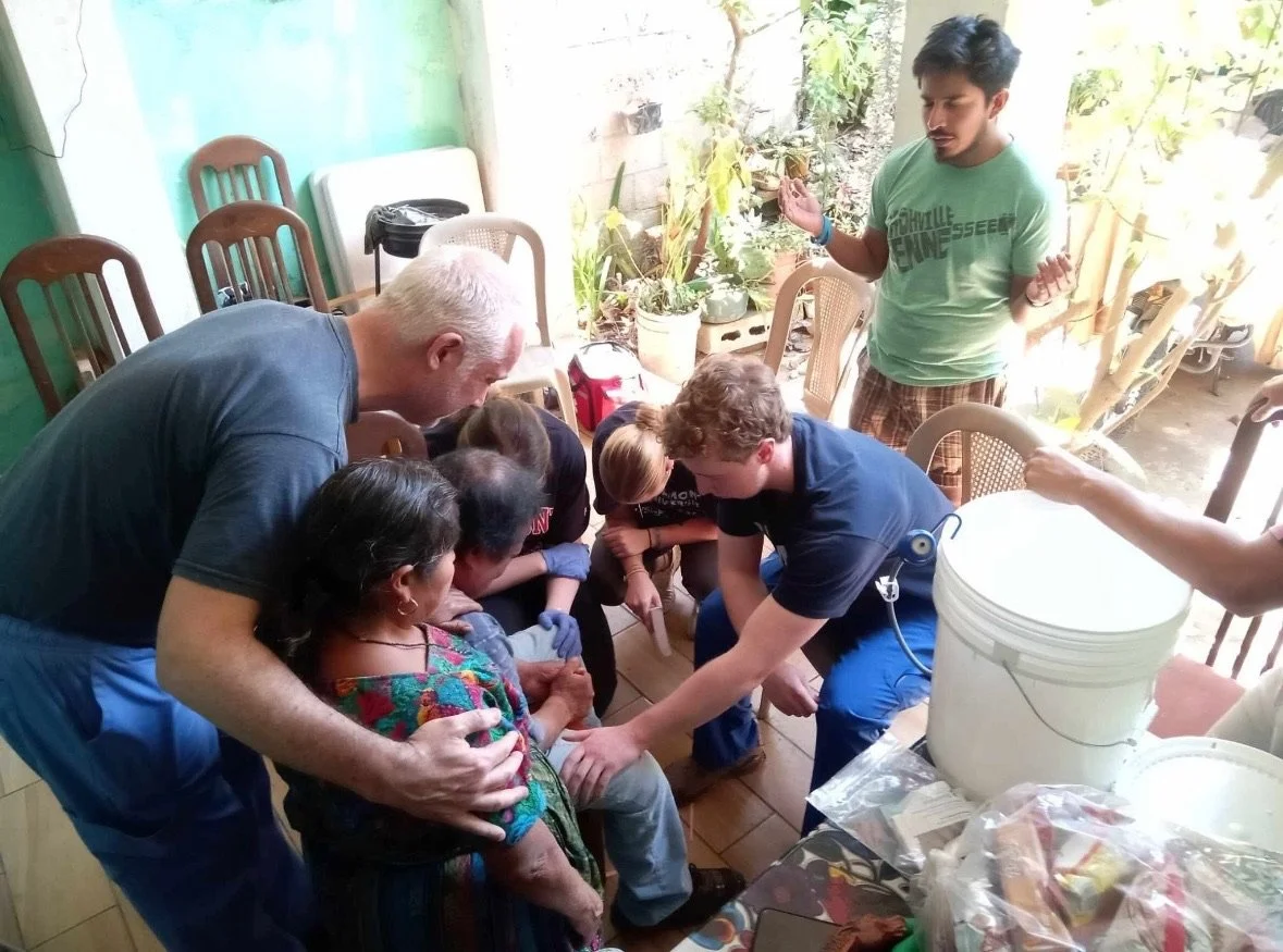 Group of volunteers praying for an elderly woman