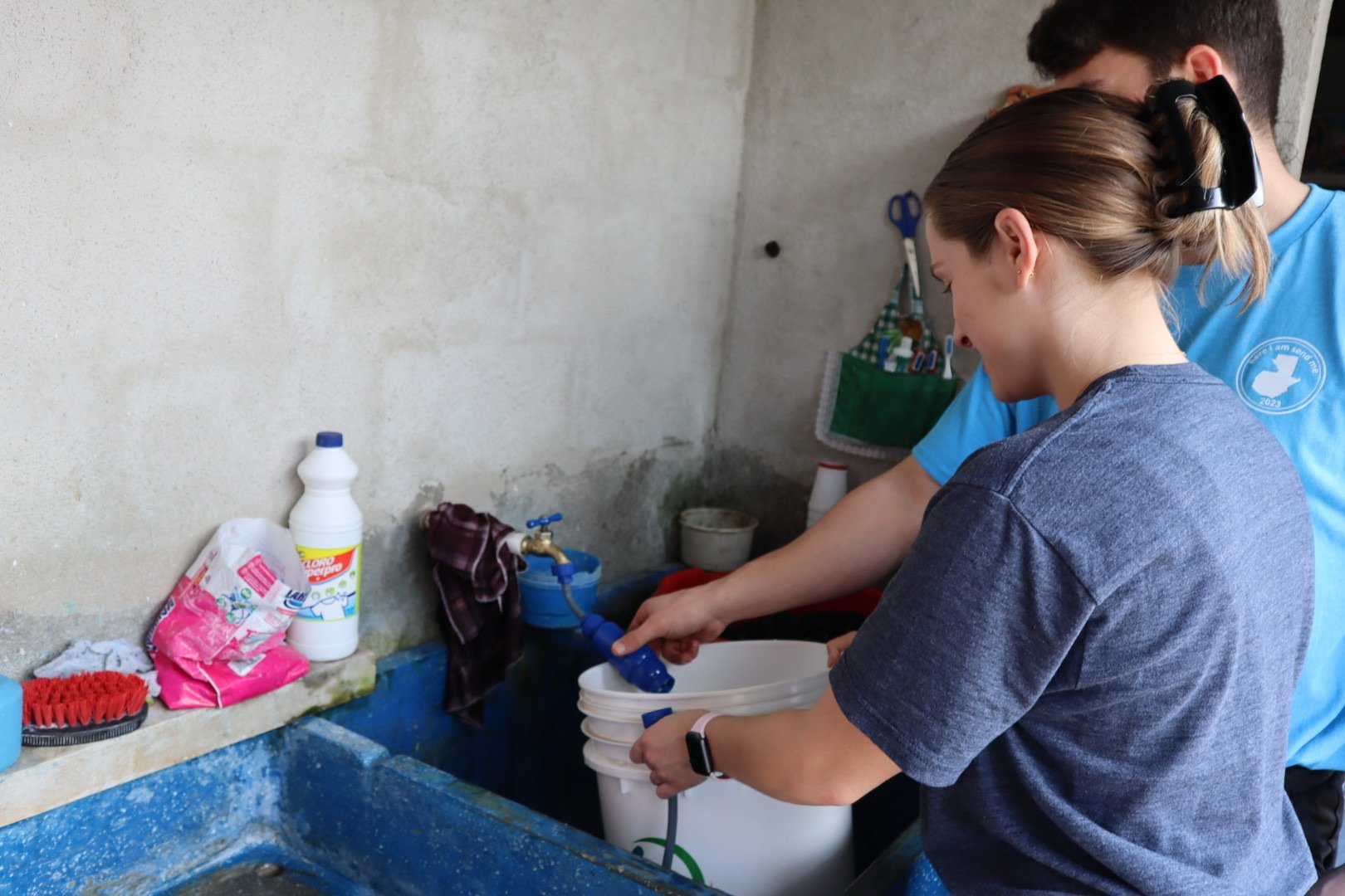 Two people assembling a water filtration system in a person's home.