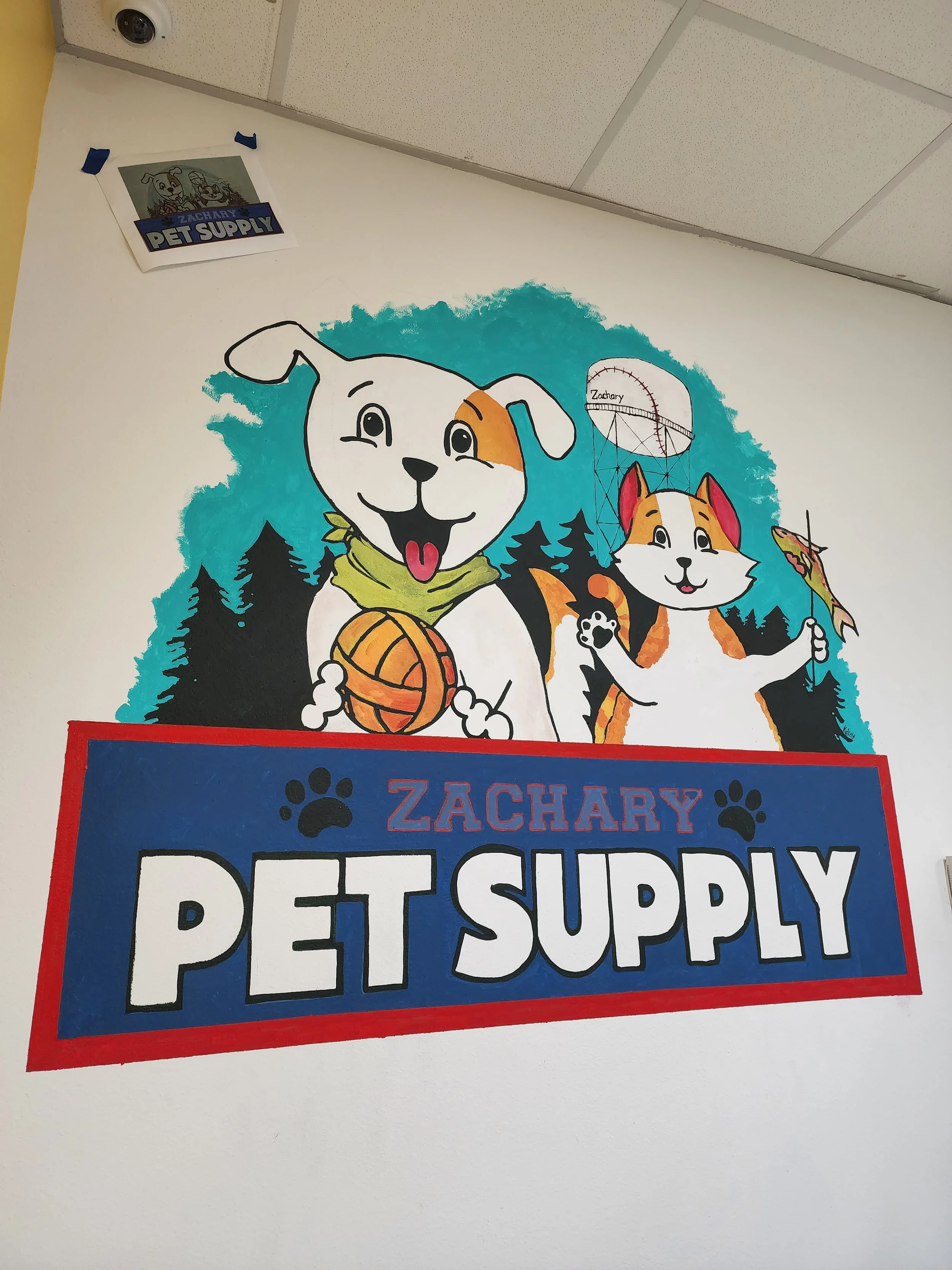 Wall mural for Zachary Pet Supply featuring cartoon dog holding a ball and cartoon cat holding an umbrella, with trees in the background.