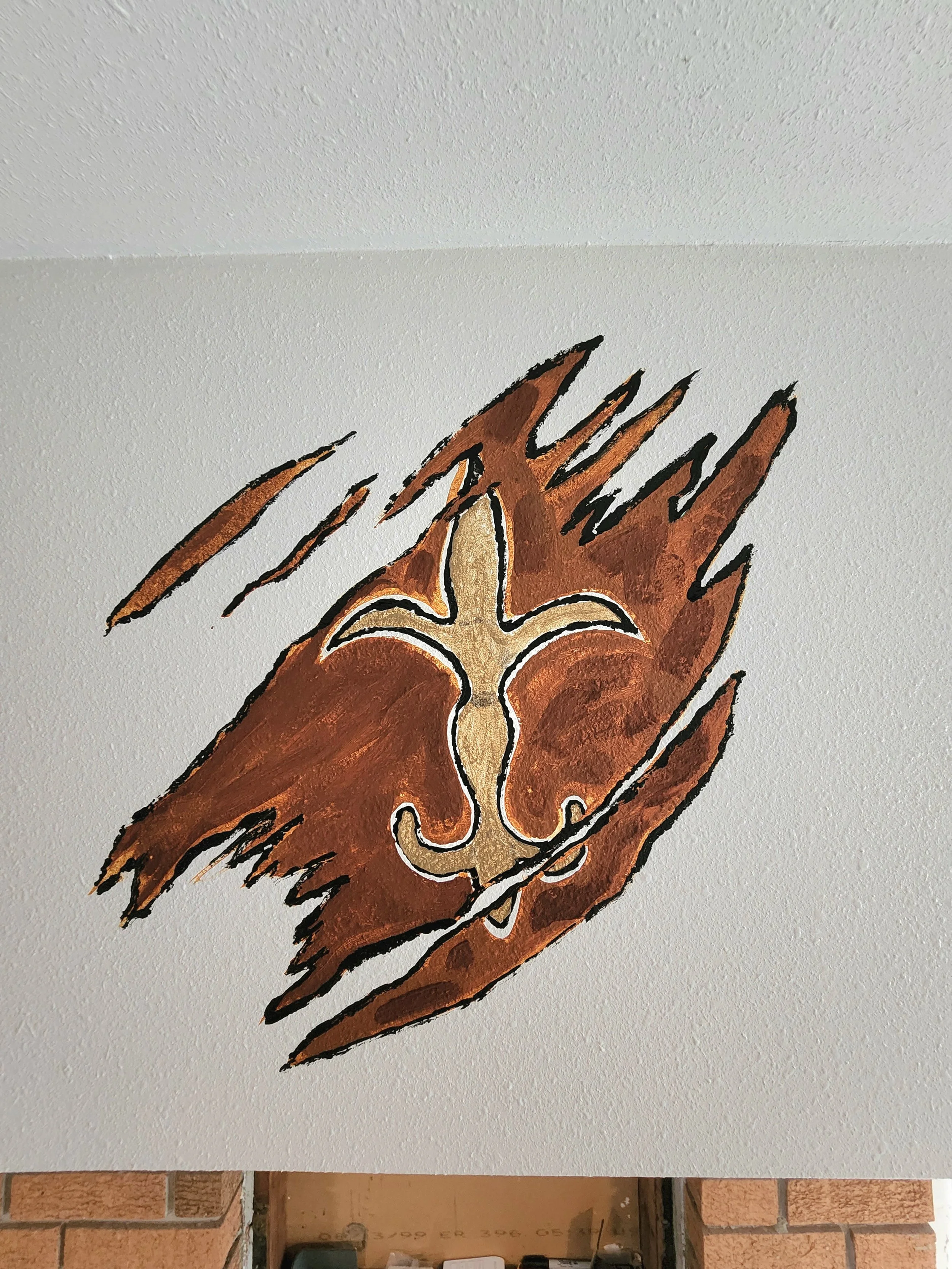 A mural of a lion's face painted in a stylized, abstract form with shades of brown, gold, and black on a white wall with a textured surface.