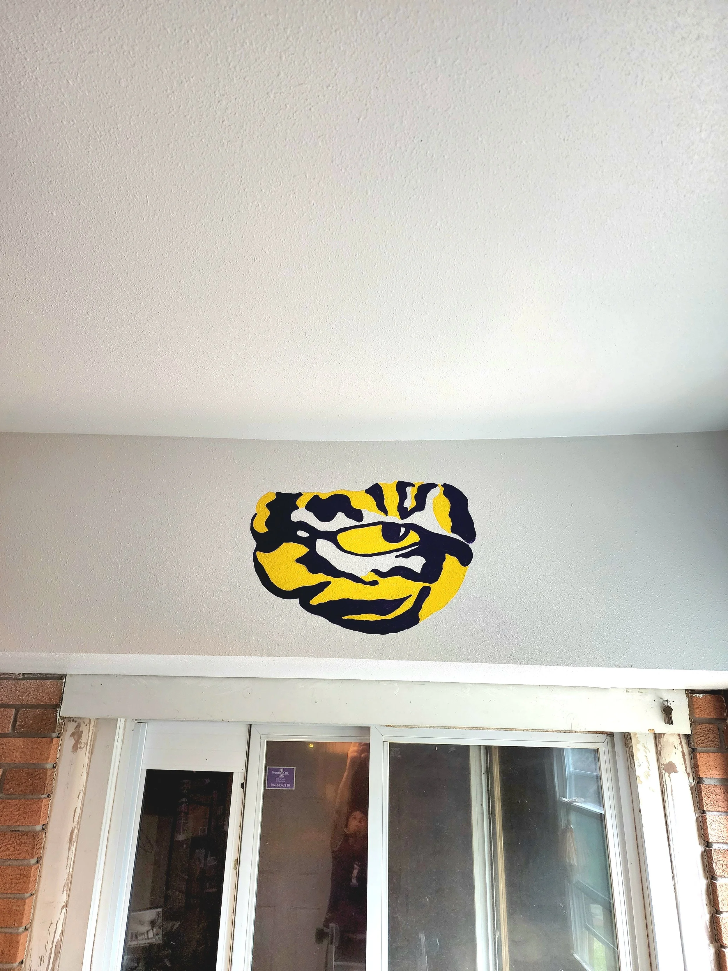 Decorative wall art featuring a stylized tiger face with yellow, black, and white design above a sliding glass door.