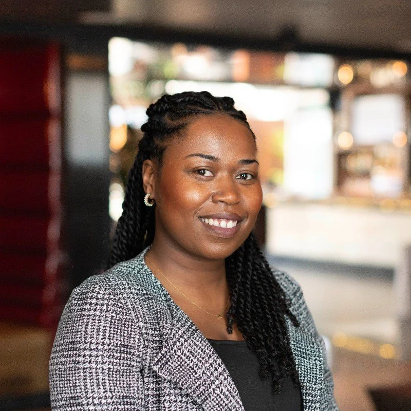 A business woman smiling at the camera in a casual indoor setting.