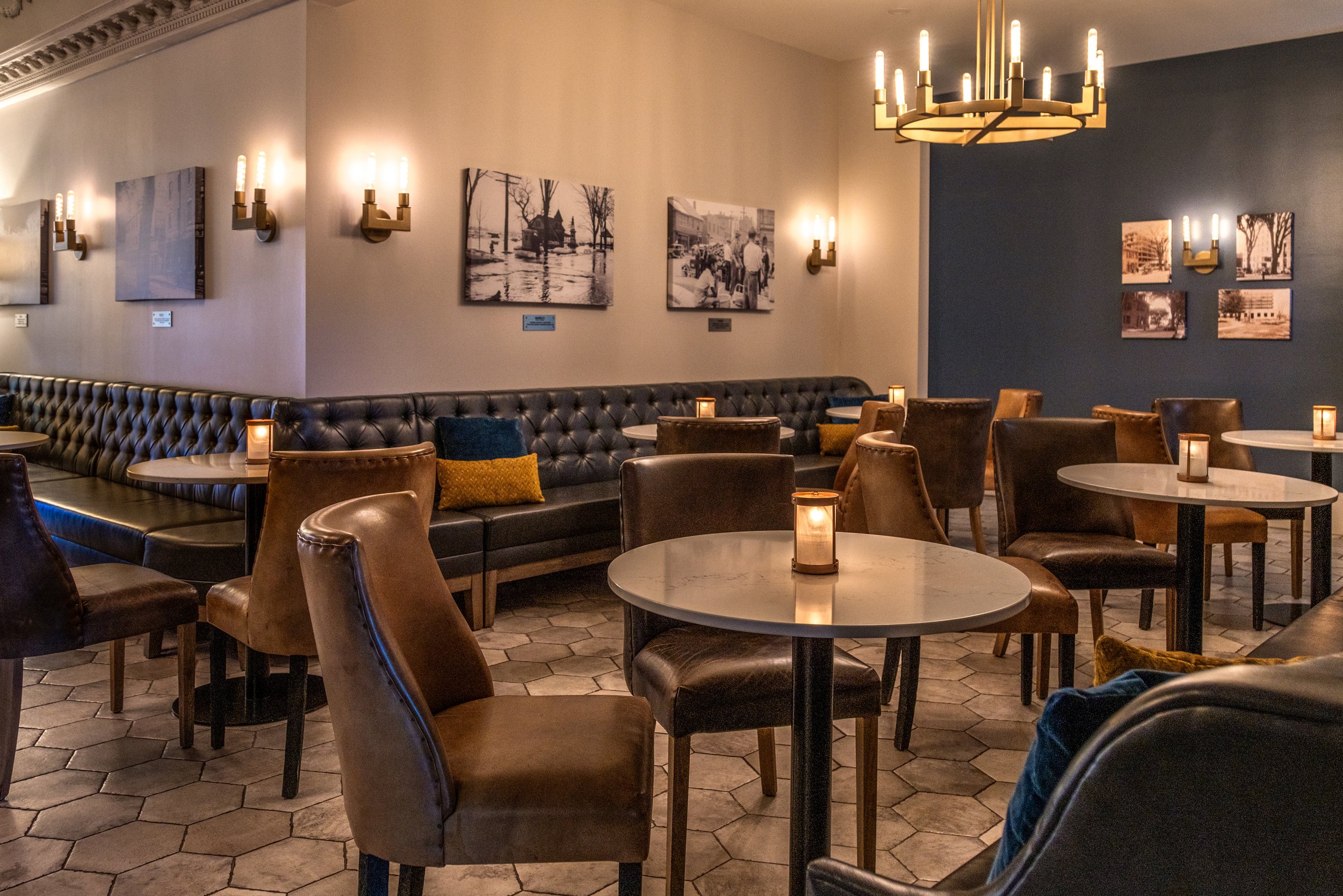 Maxwell's Steak & Seafood's cozy interior with round tables, leather chairs, candles, vintage black and white photographs on the wall, and warm lighting.